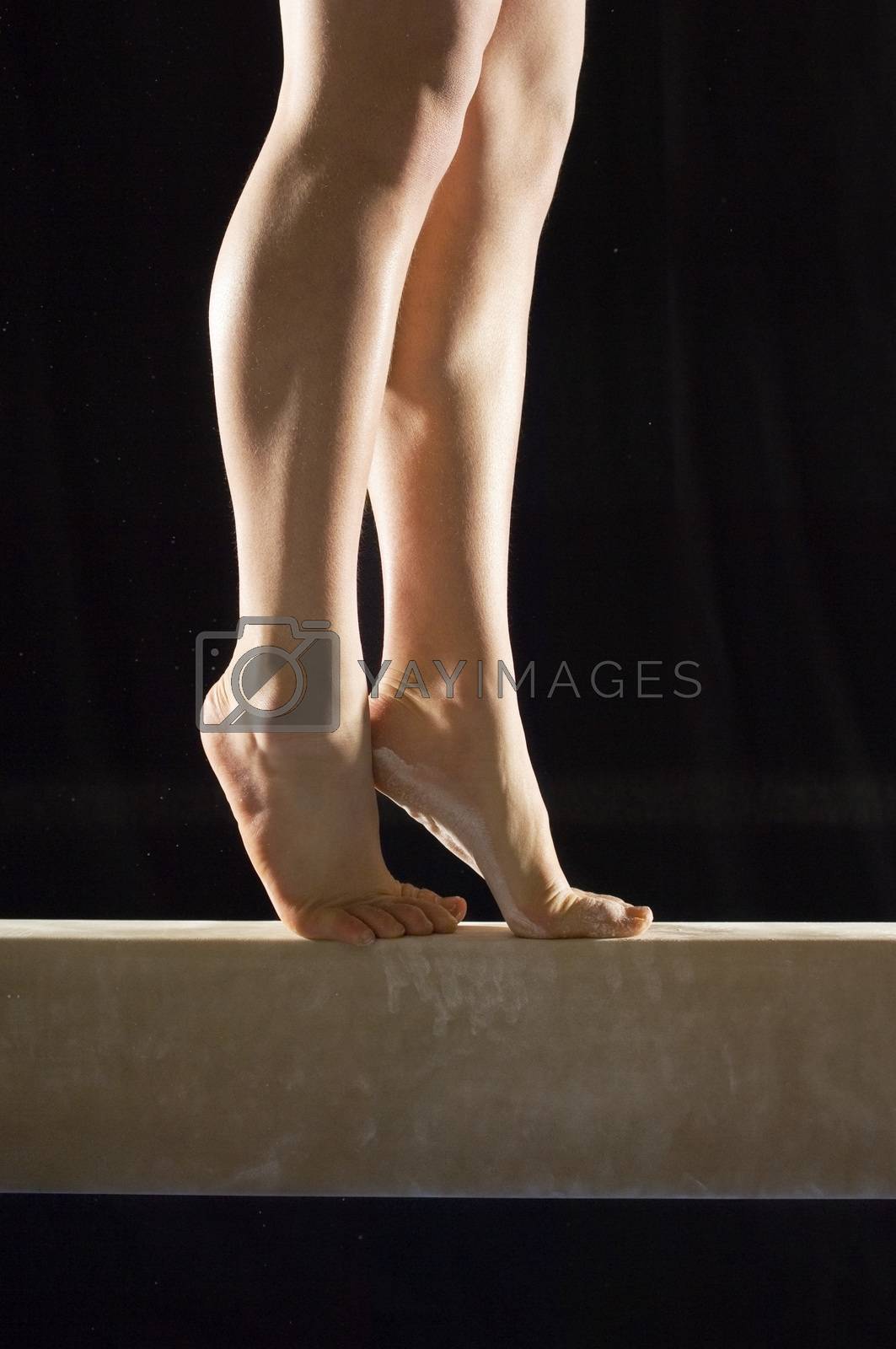Royalty free image of Closeup low section of a female gymnast on balance beam against black background by moodboard