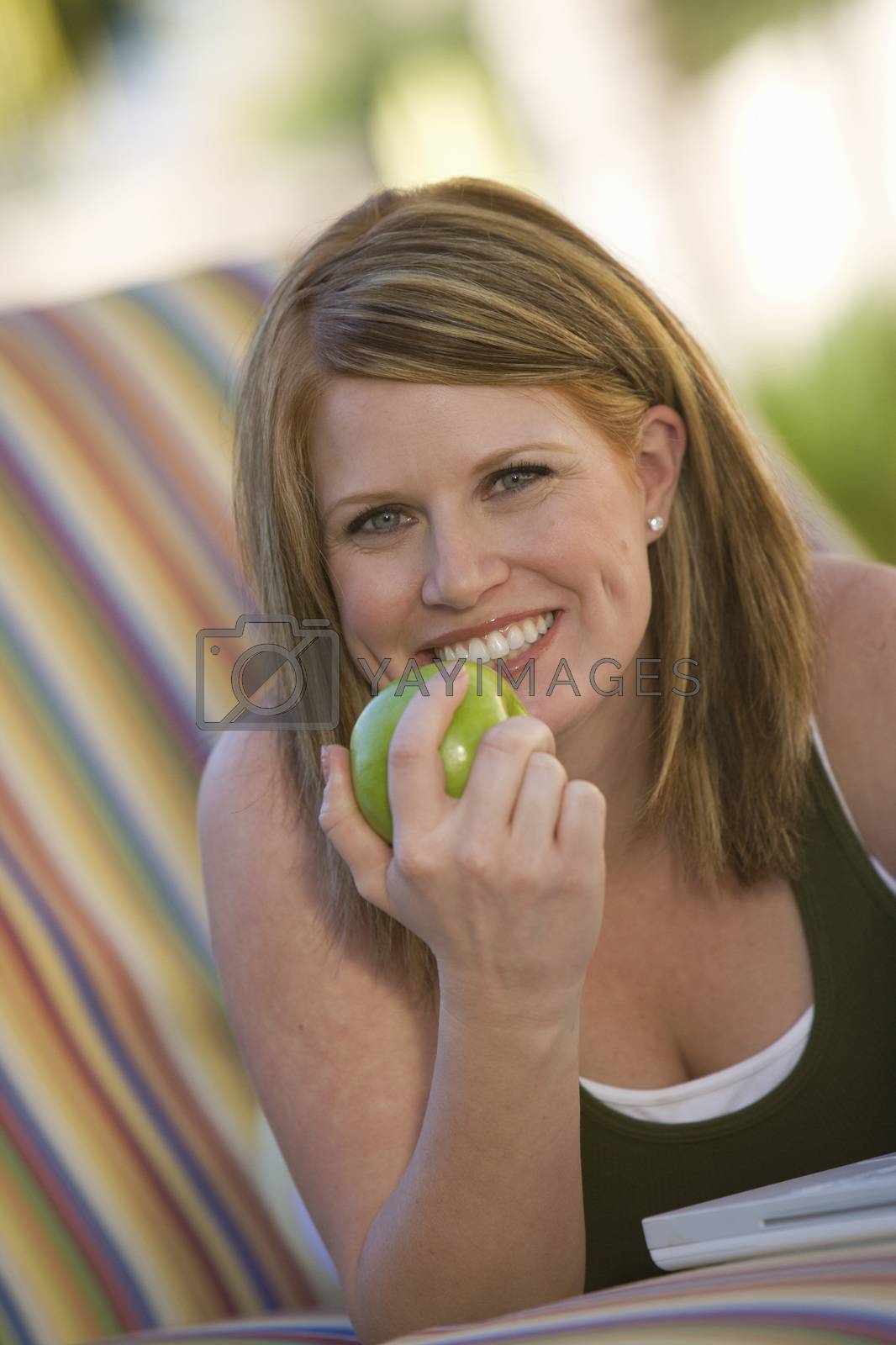 Royalty free image of Portrait of a healthy middle aged woman eating green apple by moodboard