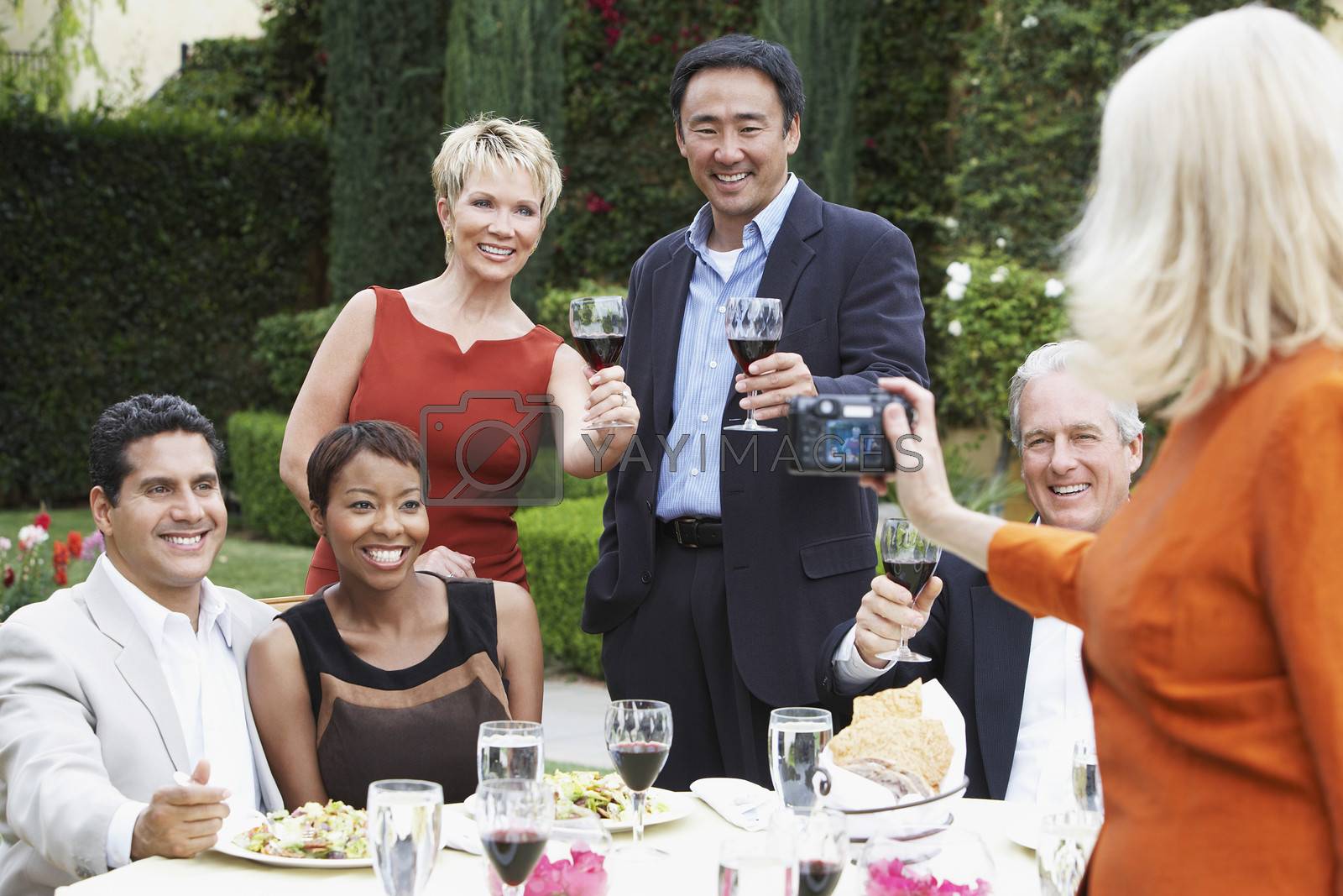 Woman photographing friends celebrating with food and drink in garden