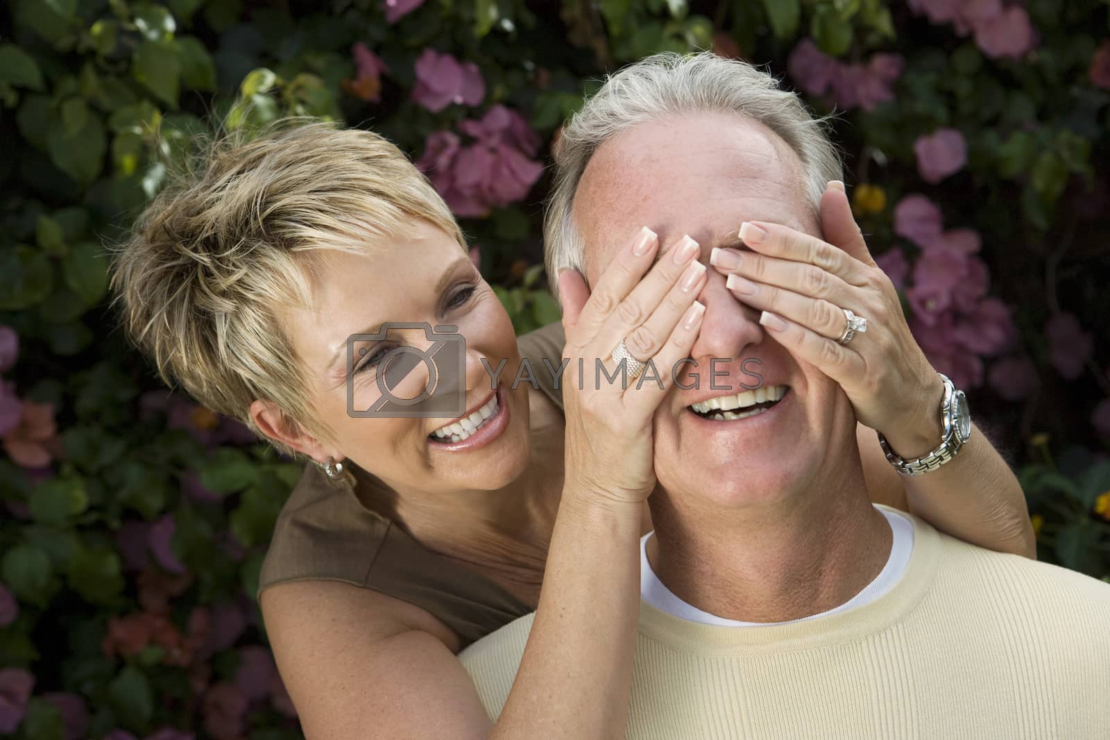 Royalty free image of Playful mature woman covering eyes of husband by moodboard