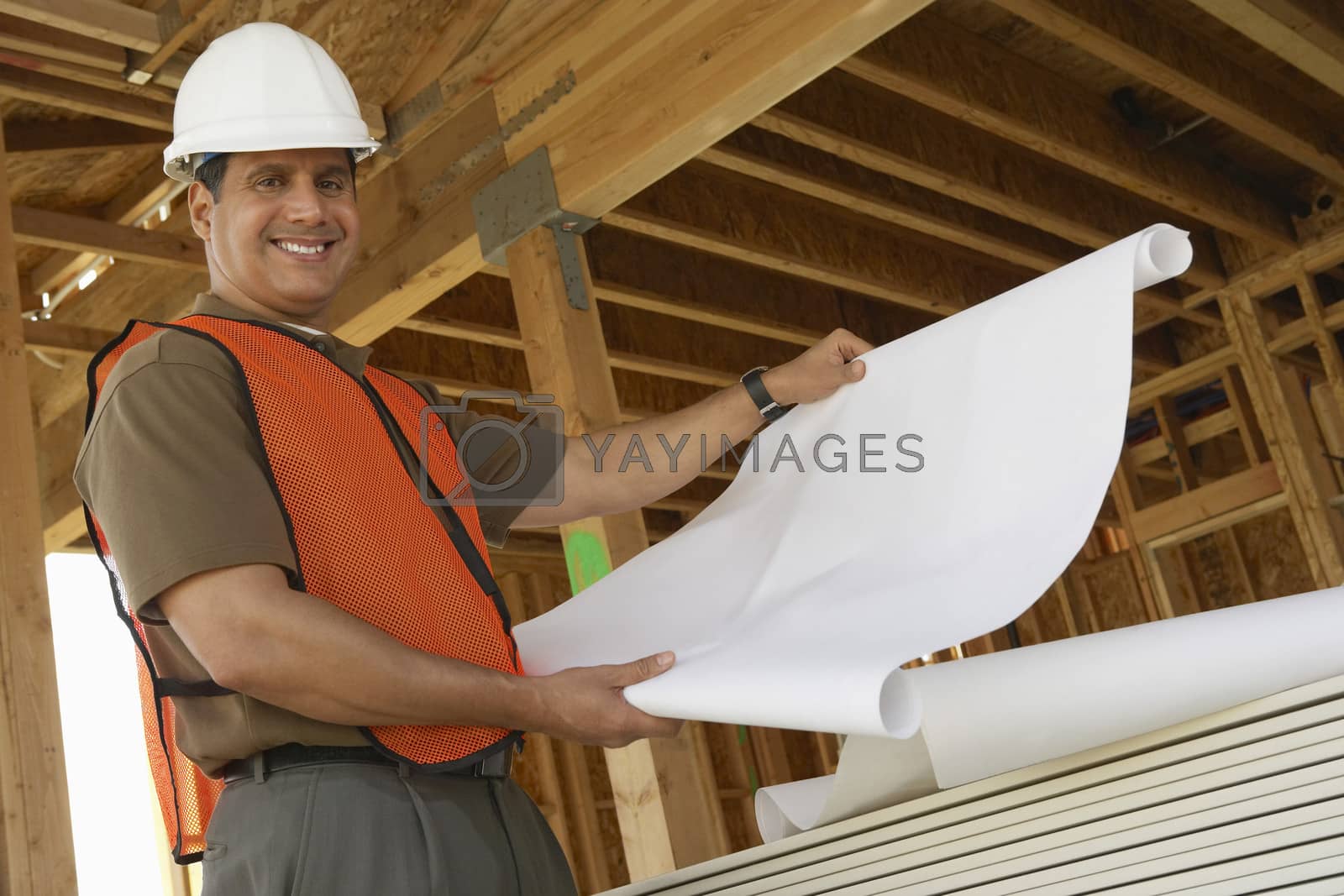 Royalty free image of Portrait of a smiling construction worker with blueprints by moodboard