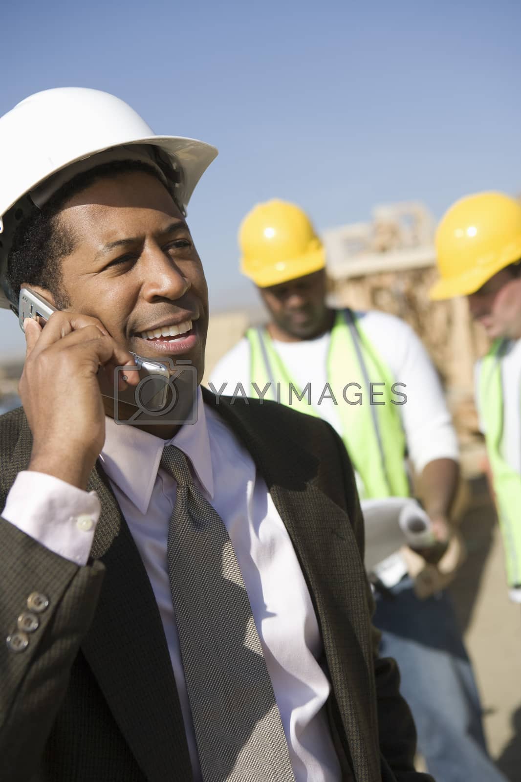 Royalty free image of An architect on a call with men in background at construction site by moodboard