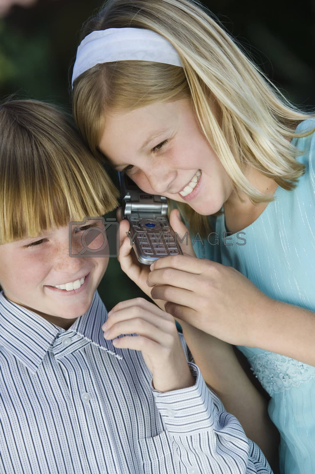 Royalty free image of Happy brother and sister communicating on cellphone together by moodboard