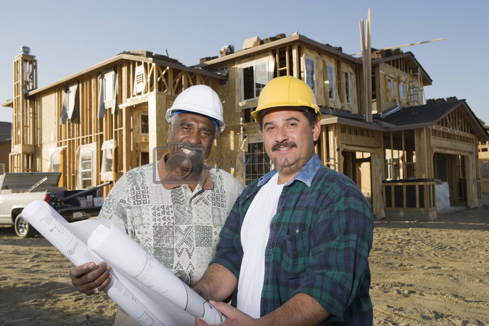 Royalty free image of Portrait of happy male architects with blueprint in front of incomplete house by moodboard