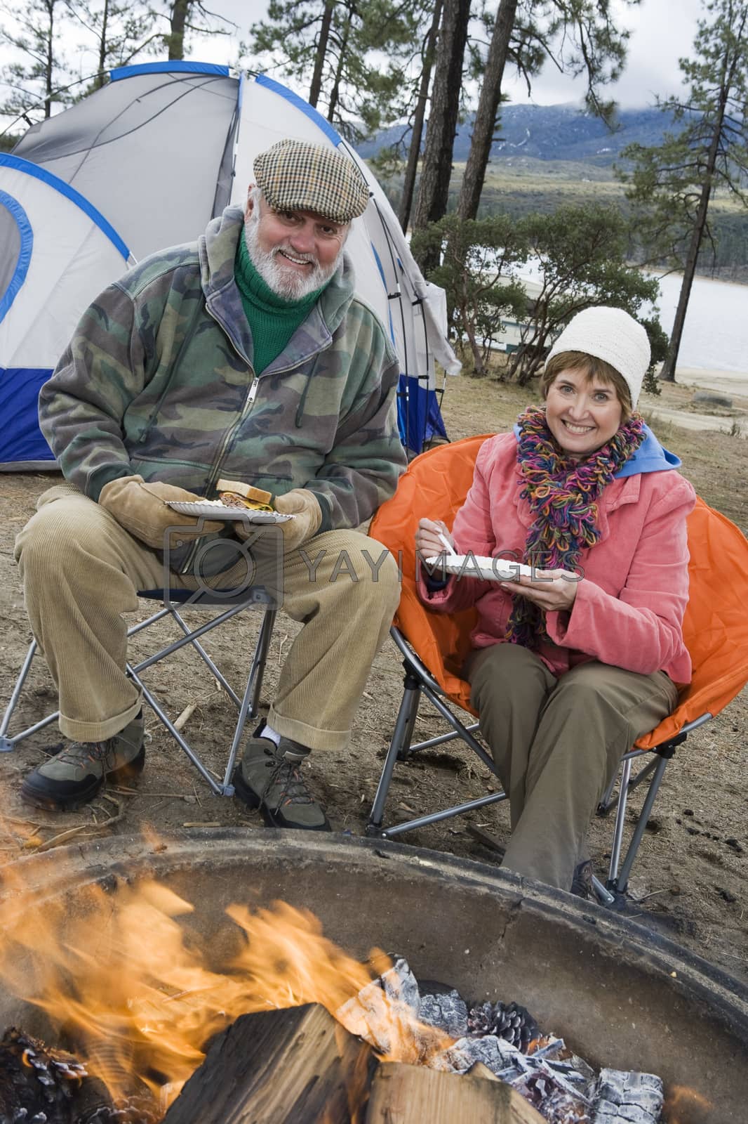Royalty free image of Portrait of happy senior couple having food at campfire by moodboard