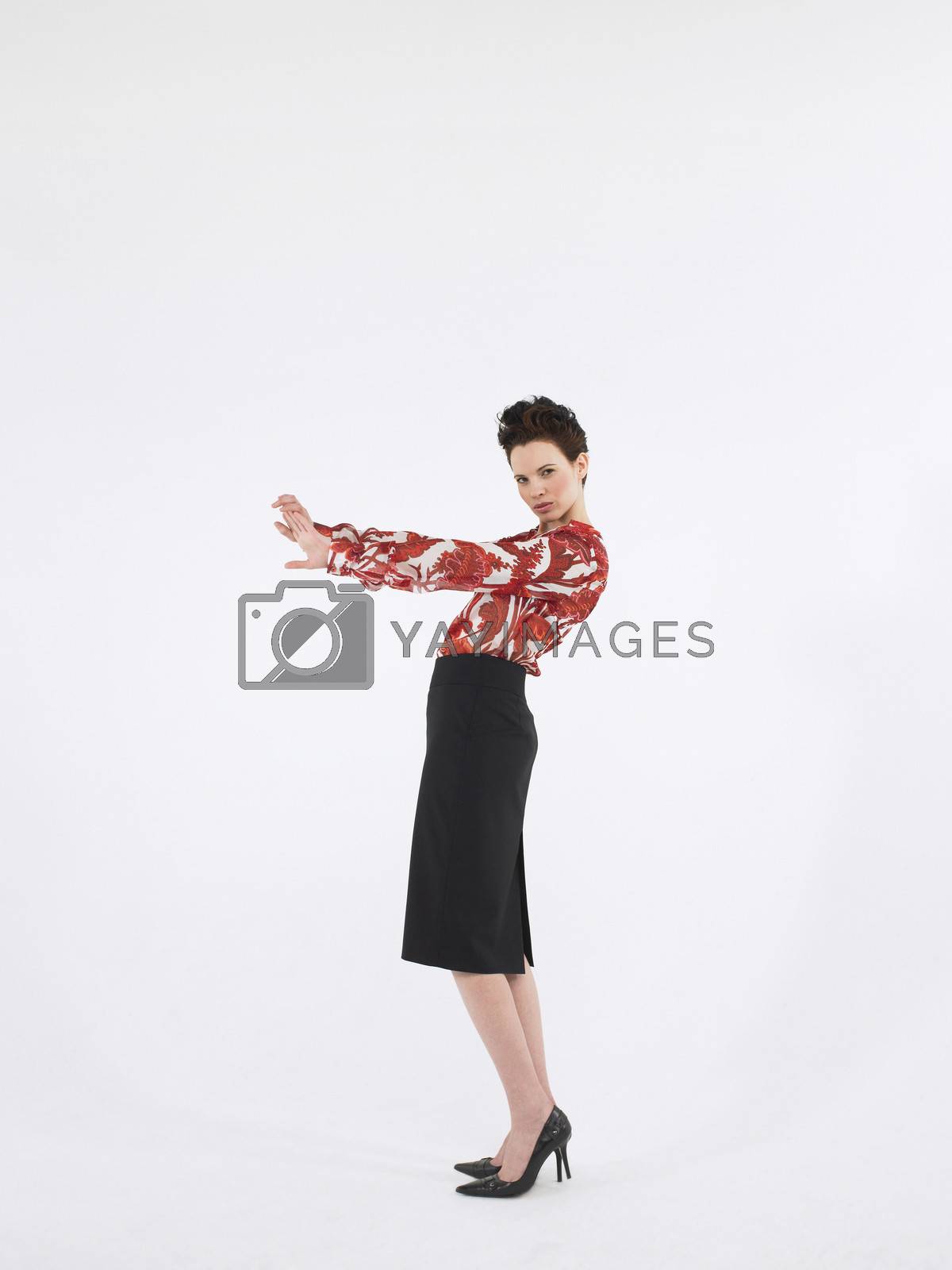 Royalty free image of Full length side view of a young woman with hand gestures posing against white background by moodboard