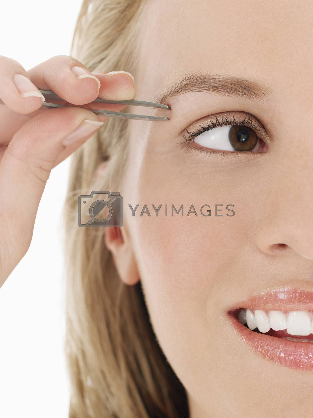 Royalty free image of Young Woman plucking Eyebrow close up cropped by moodboard