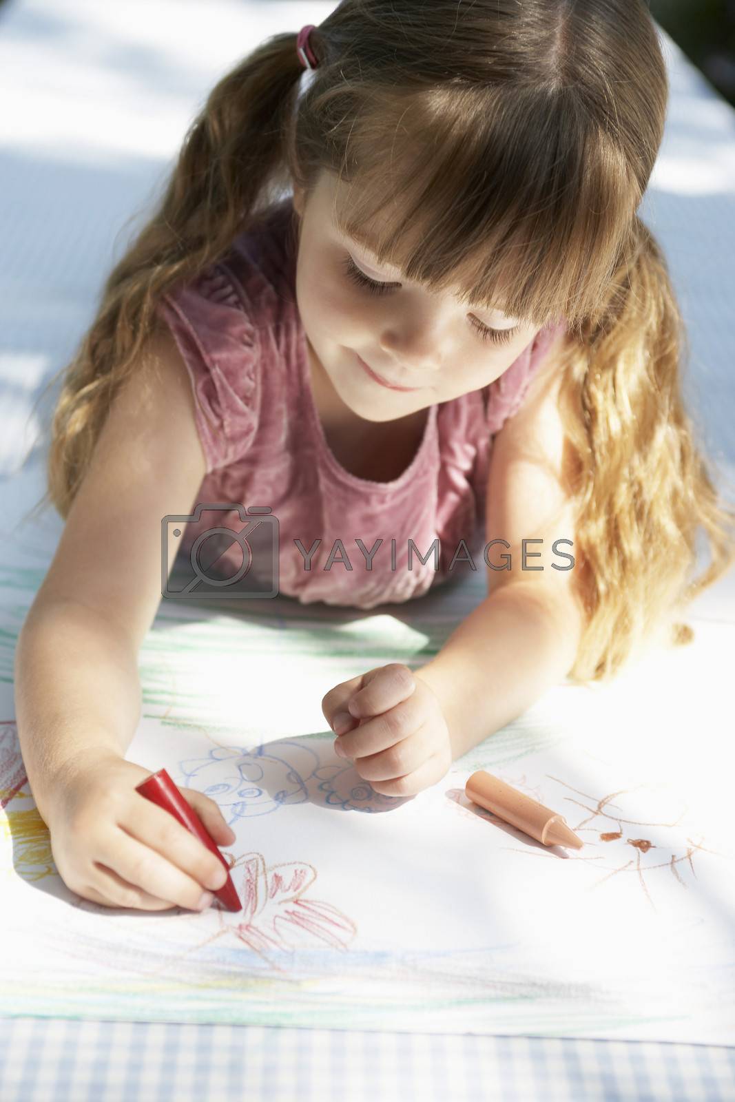 Royalty free image of Young girl lying on backyard table and drawing by moodboard