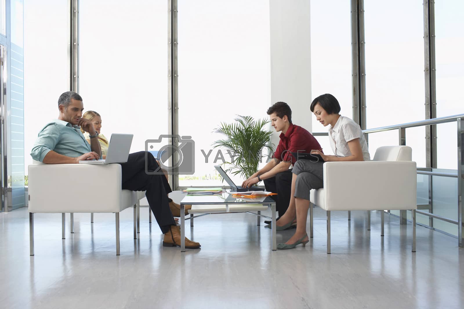 Royalty free image of Full length side view of four business people sitting in modern waiting room at office by moodboard
