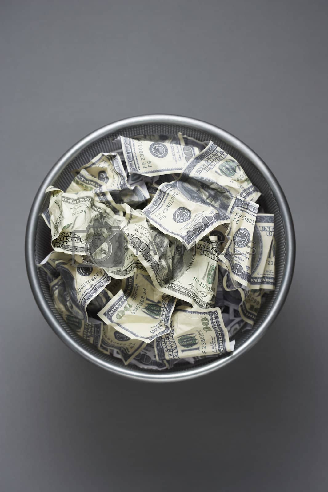 Royalty free image of Dollar bills in wastebasket view from above by moodboard
