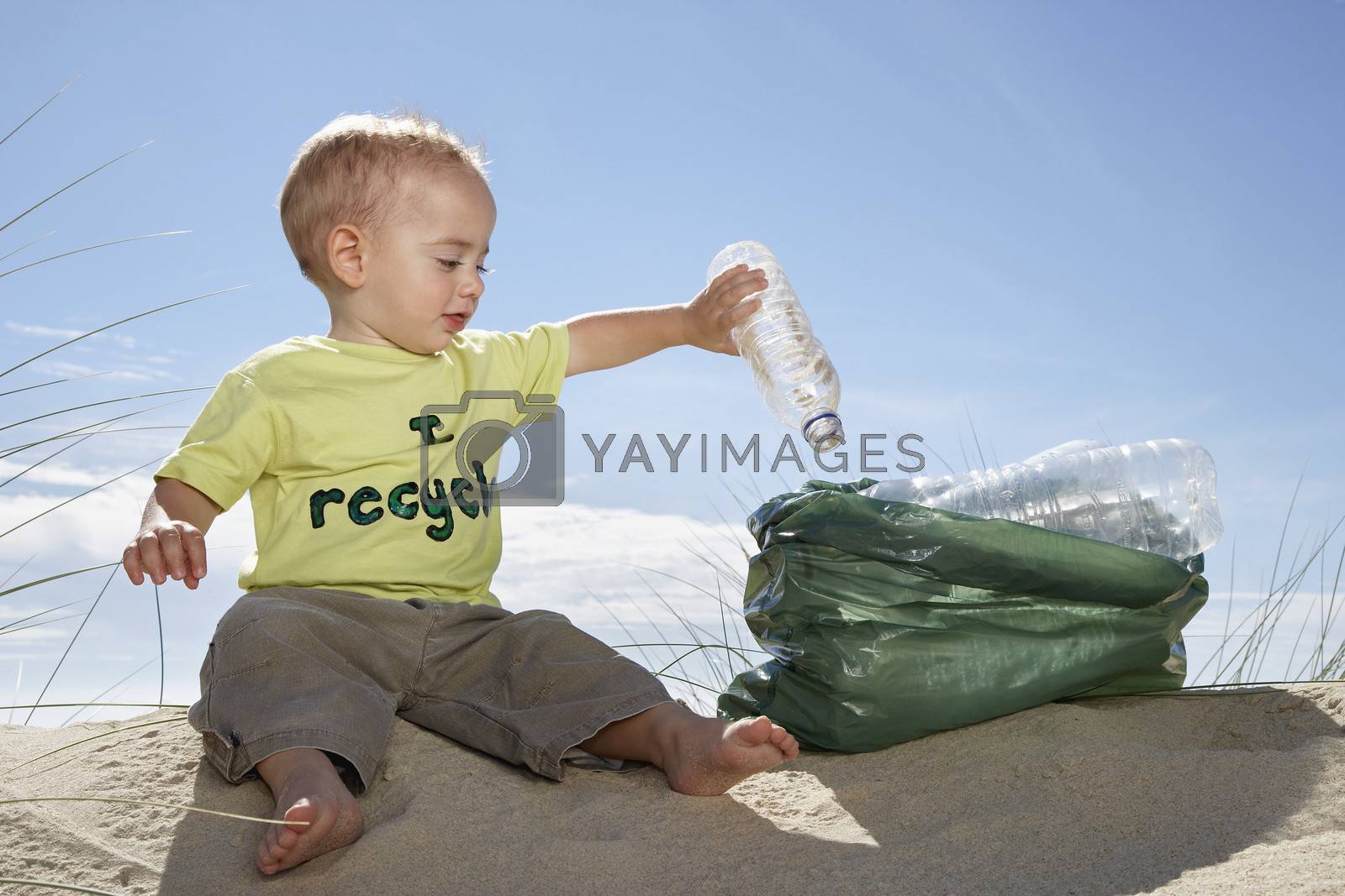 Royalty free image of Boy (1-2) playing with plastic bottles on sand dune by moodboard