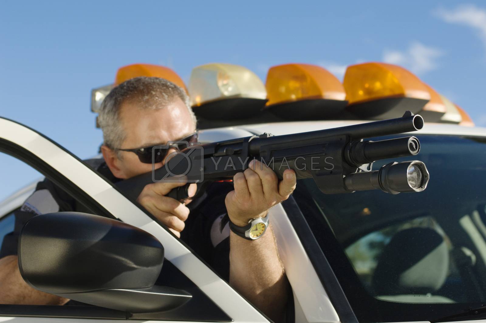 Royalty free image of Police officer aiming through gun while hiding behind car by moodboard