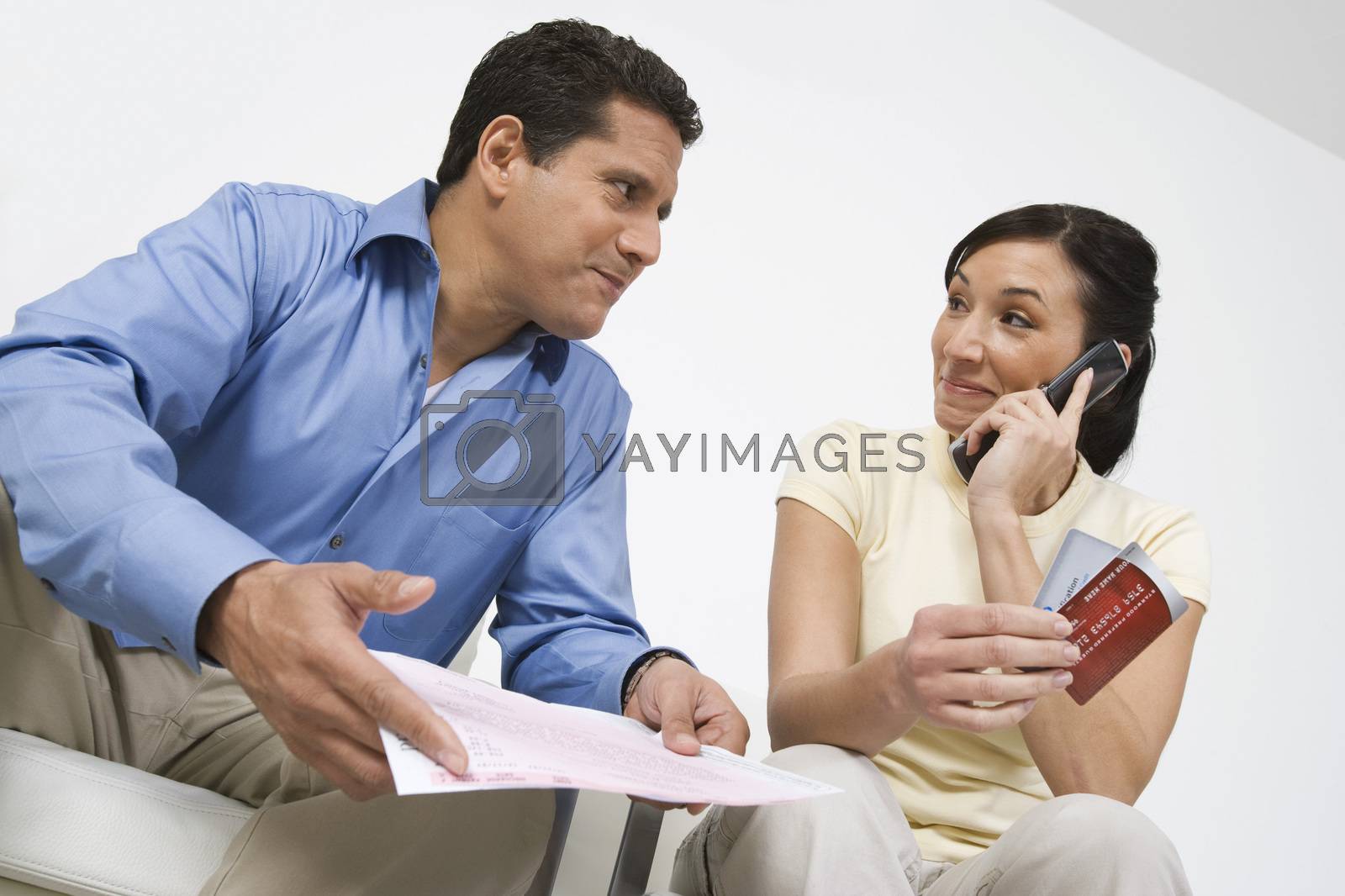 Royalty free image of Woman with credit cards on call looking at man holding bill by moodboard