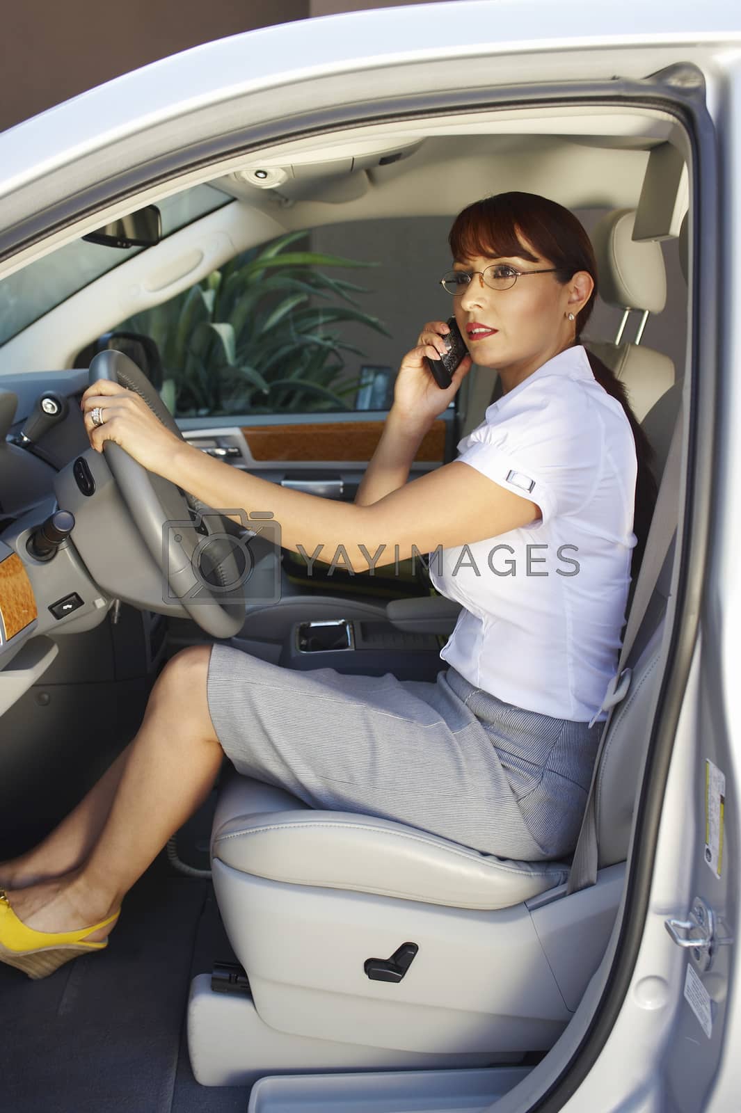 Royalty free image of Business woman using mobile phone in car by moodboard