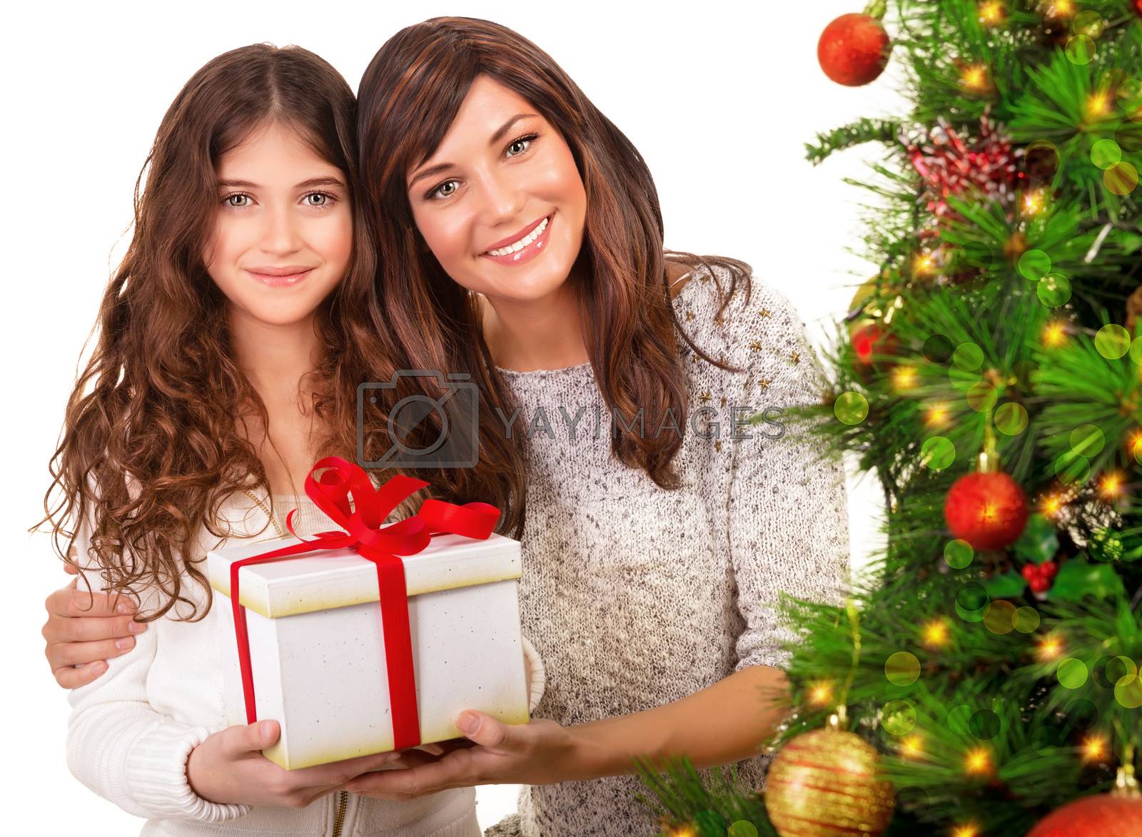 Closeup portrait of attractive mother with cute daughter holding in hands festive gift box, beautiful decorated Christmas tree, copy space