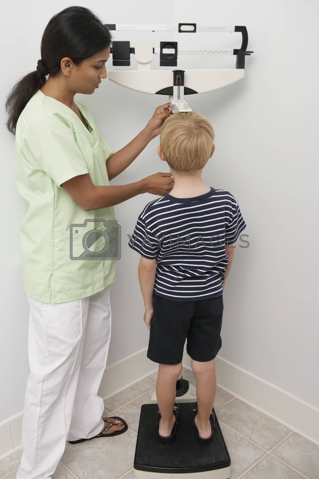 Royalty free image of Female nurse weighting young patient by moodboard