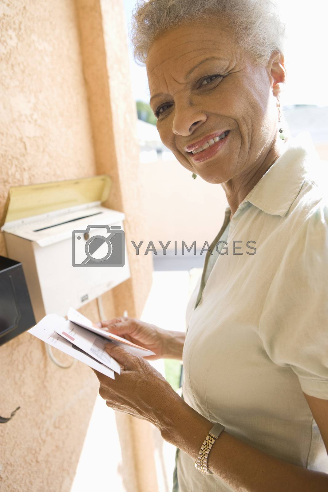 Royalty free image of Woman collecting mail from letterbox by moodboard