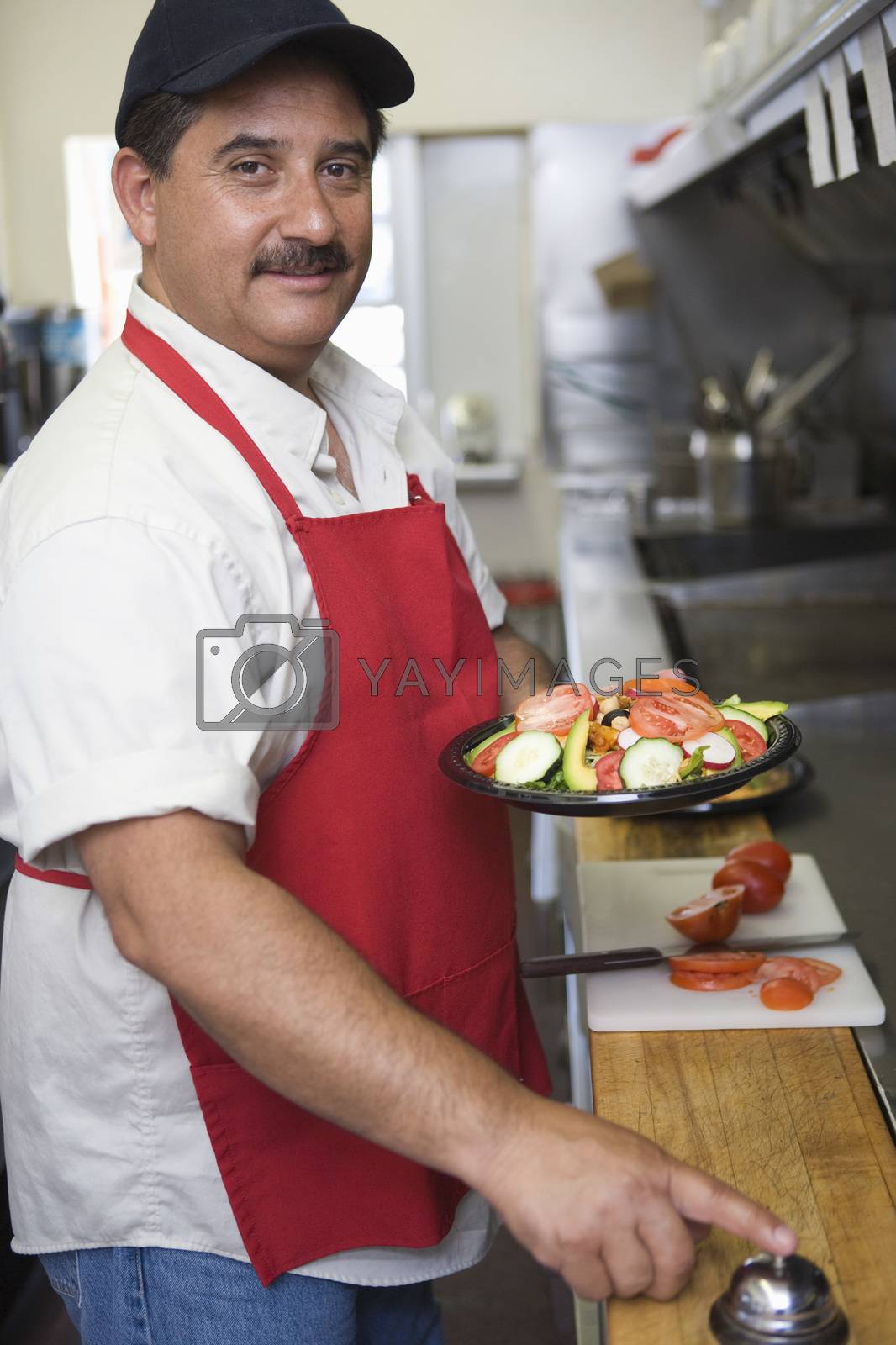 Royalty free image of Portrait of Hispanic Latin man ringing bell with food ready to serve by moodboard
