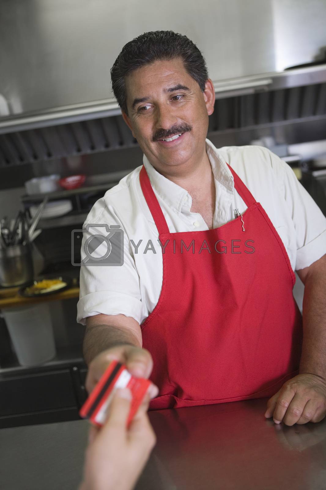 Royalty free image of Hispanic Latin male owner receiving payment from customer in restaurant by moodboard