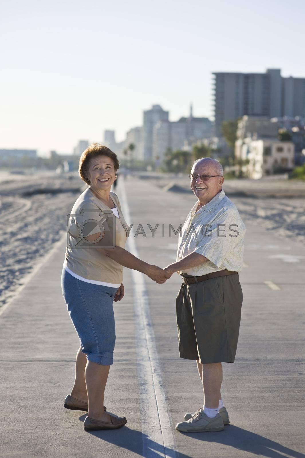 Royalty free image of Senior couple on promenade holding hands by moodboard