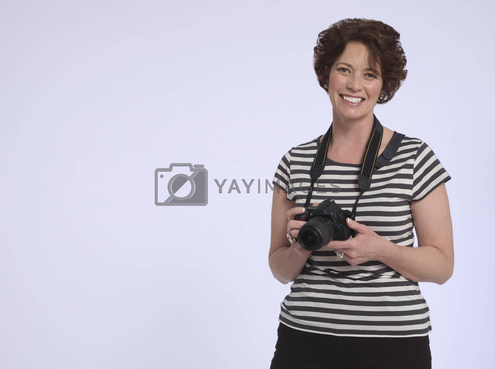 Royalty free image of Portrait of mid adult woman holding digital camera studio shot by moodboard