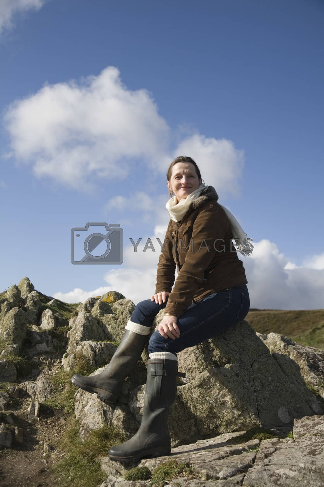 Royalty free image of Mature woman sitting on a rock by moodboard