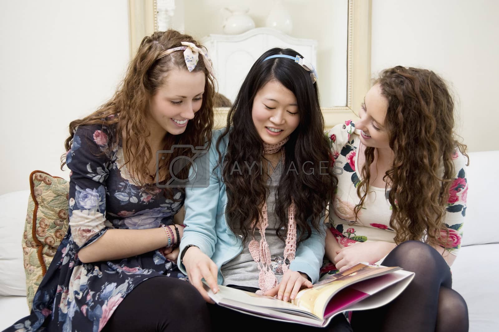 Royalty free image of Young women looking at magazines on a sofa by moodboard