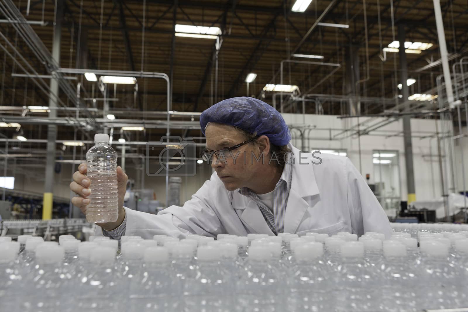 Royalty free image of Quality control worker checking bottled water at bottling plant by moodboard