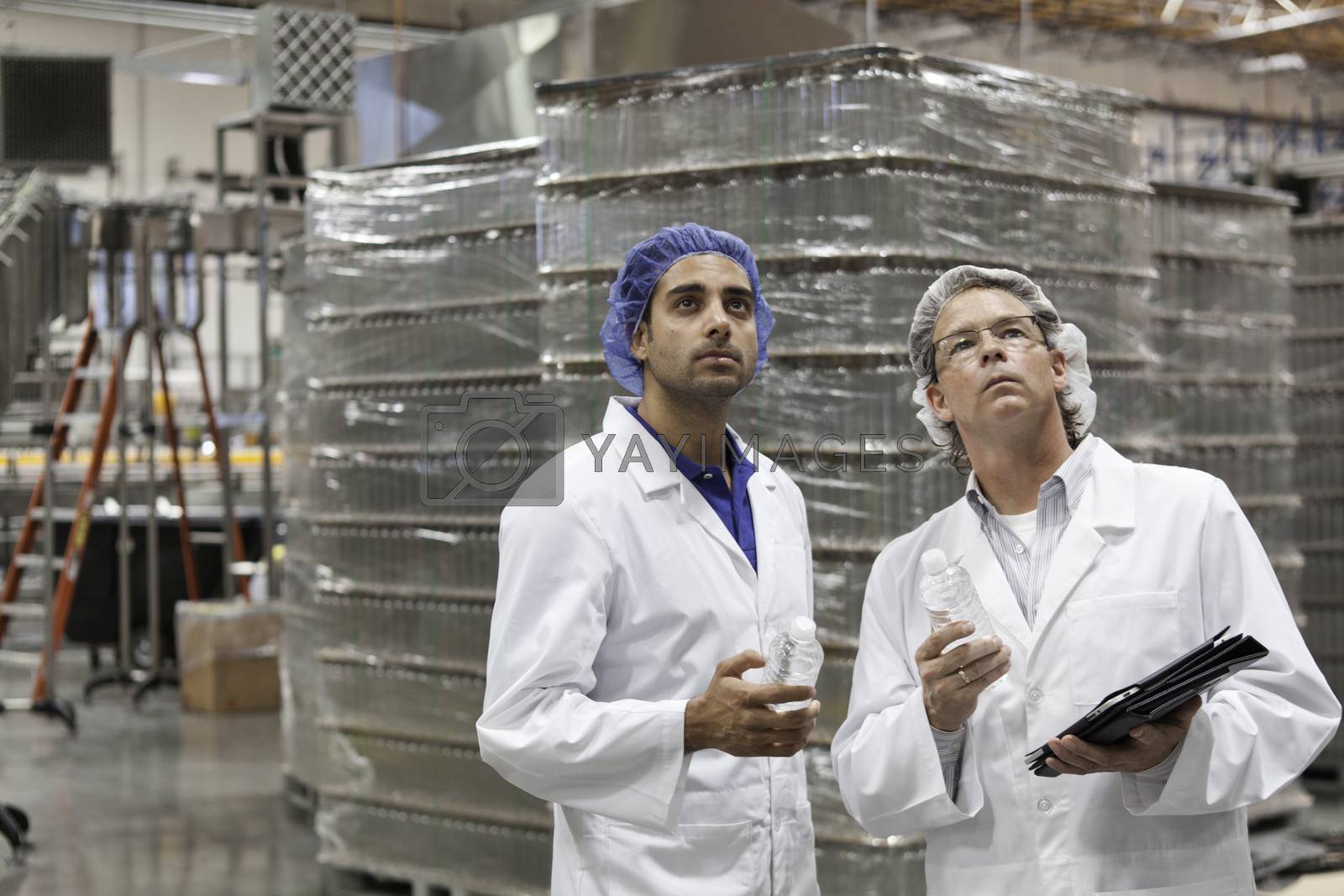 Royalty free image of Quality control workers inspecting at bottling plant by moodboard