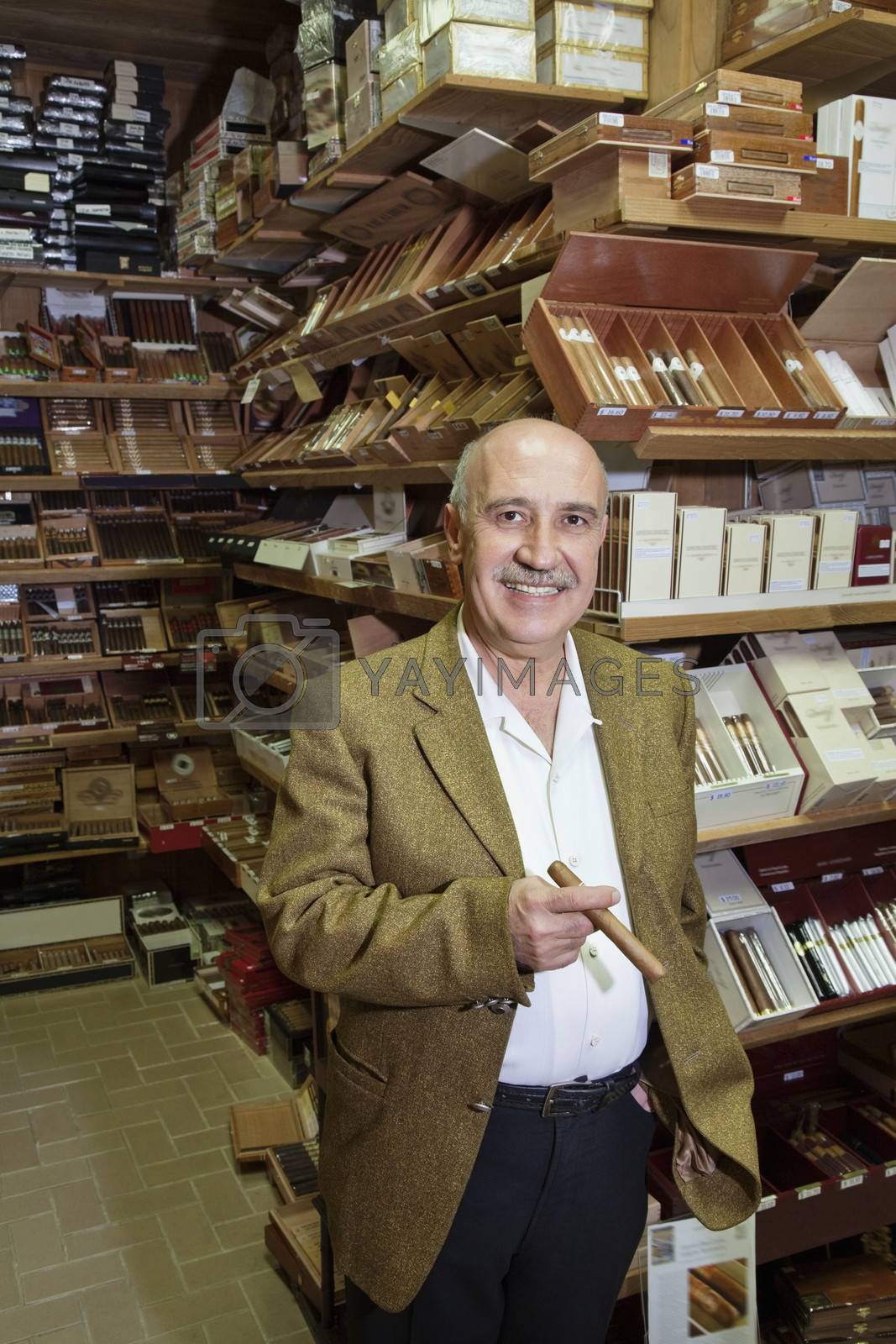 Royalty free image of Portrait of a happy standing in front of cigar display by moodboard