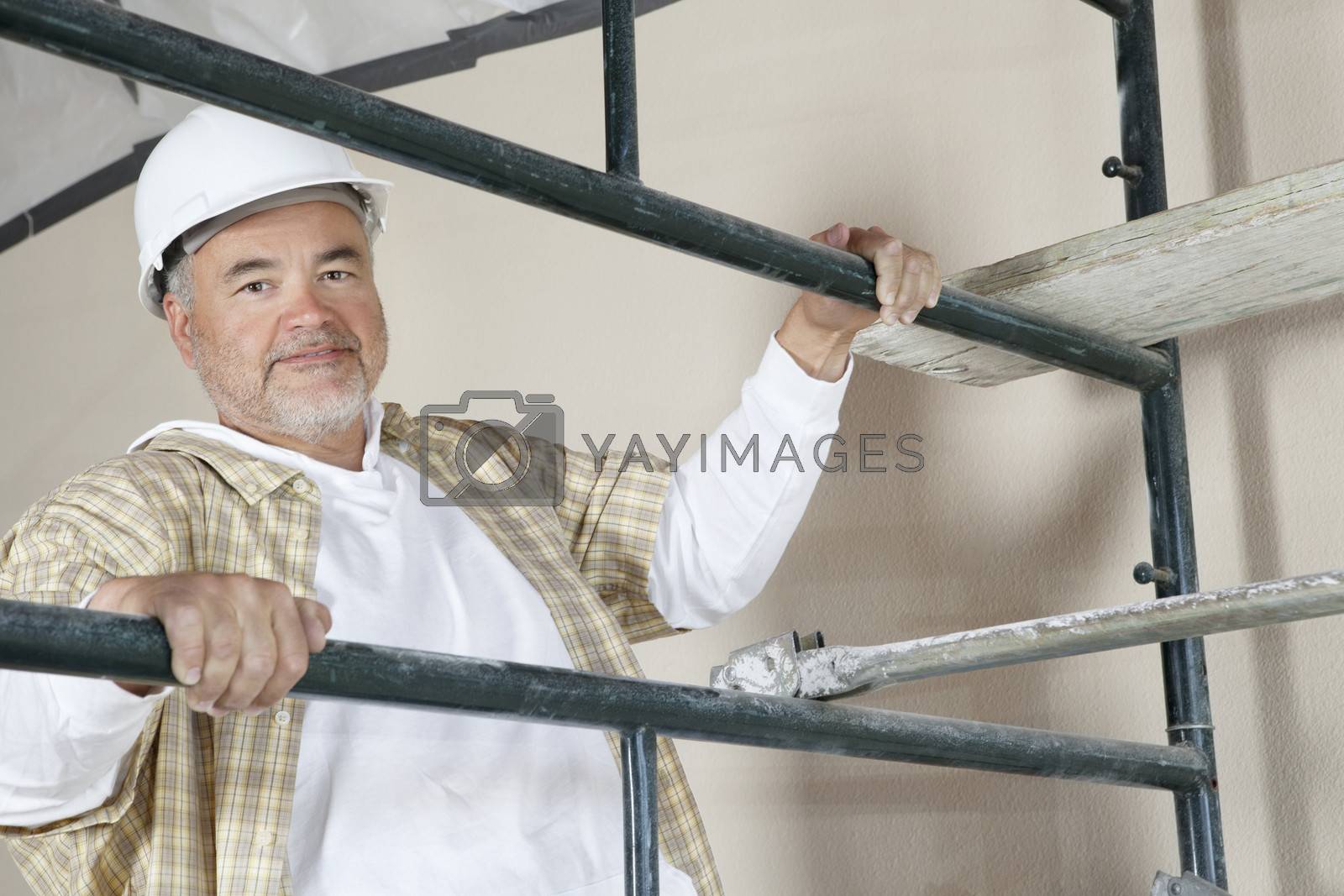 Royalty free image of Portrait of mature man climbing scaffold by moodboard