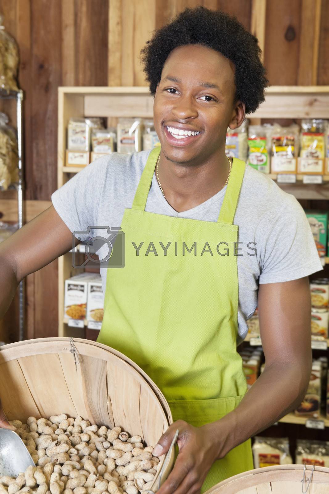 Royalty free image of Male African American store clerk holding basket of peanuts by moodboard