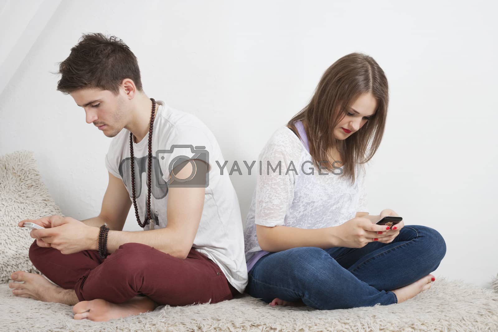 Royalty free image of Friends text messaging with cell phone while sitting on sofa by moodboard