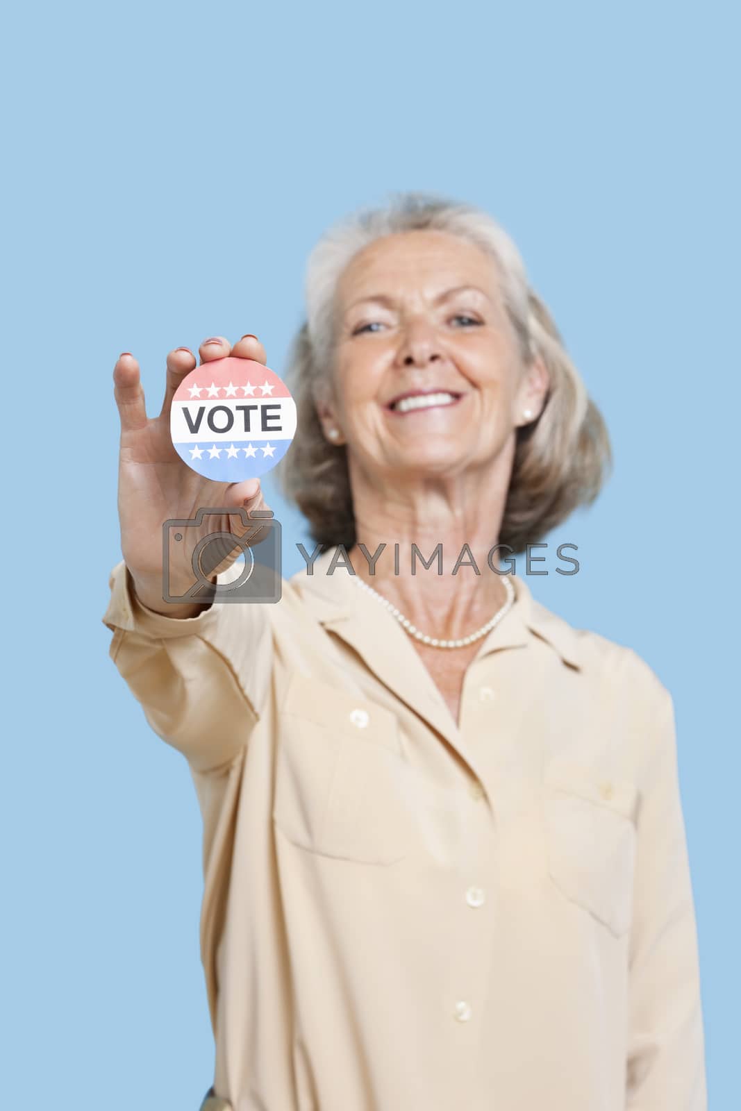 Royalty free image of Portrait of senior woman holding an election badge against blue background by moodboard