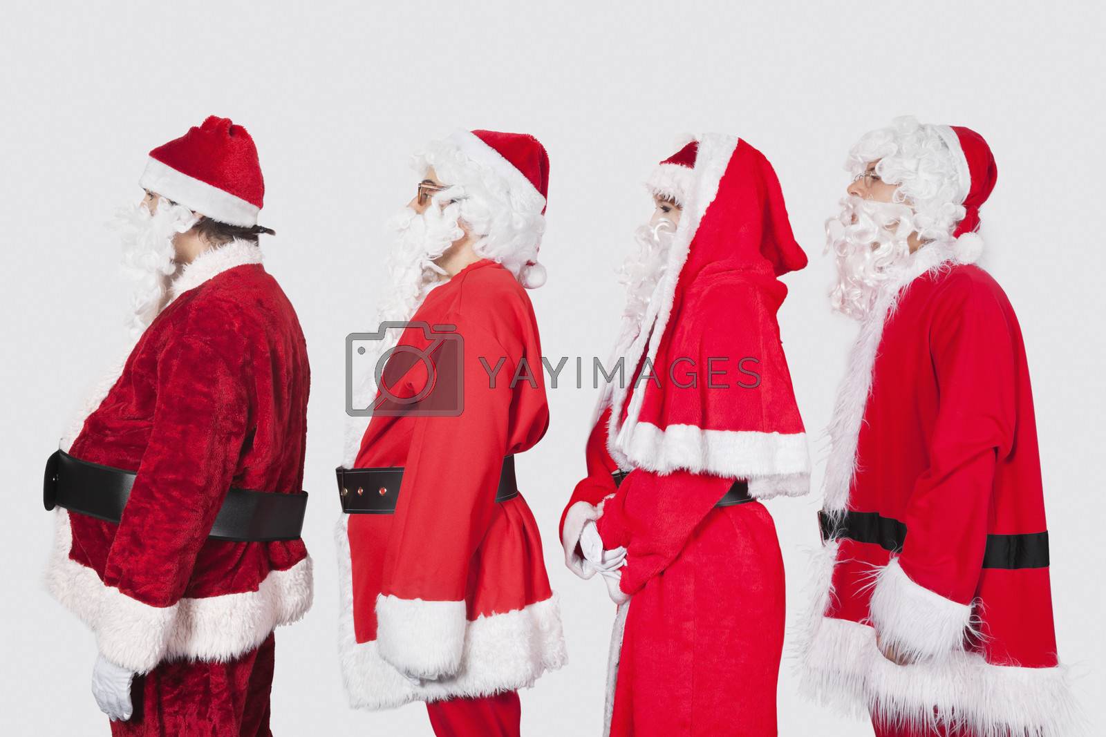 Royalty free image of People in Santa costume standing in row against gray background by moodboard