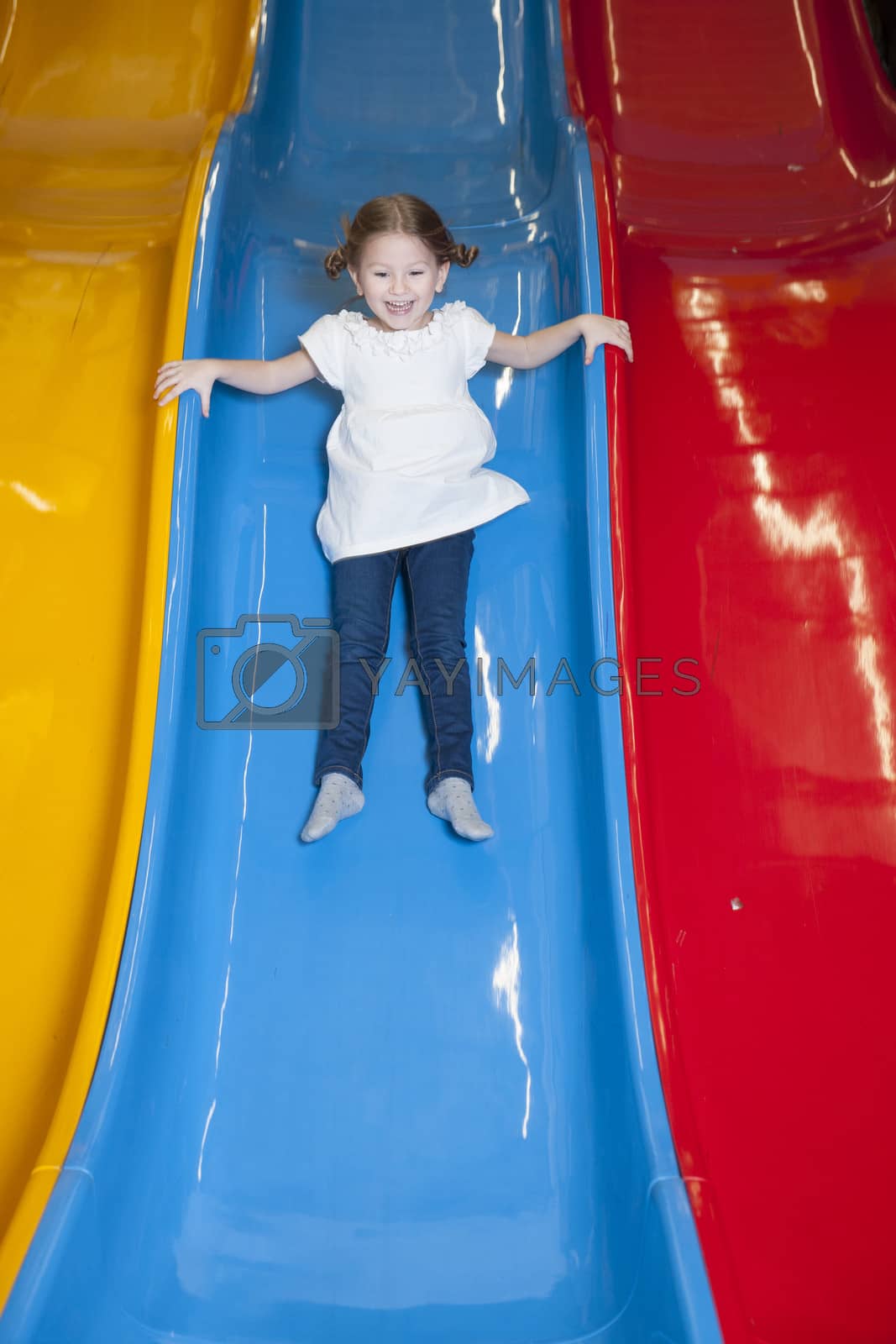 Royalty free image of Young girl slides down colorful slide by moodboard