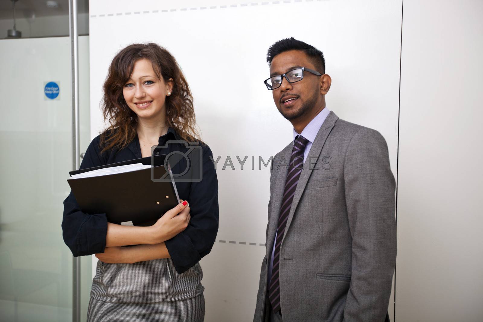Royalty free image of Work colleagues stand together in meeting room smiling by moodboard