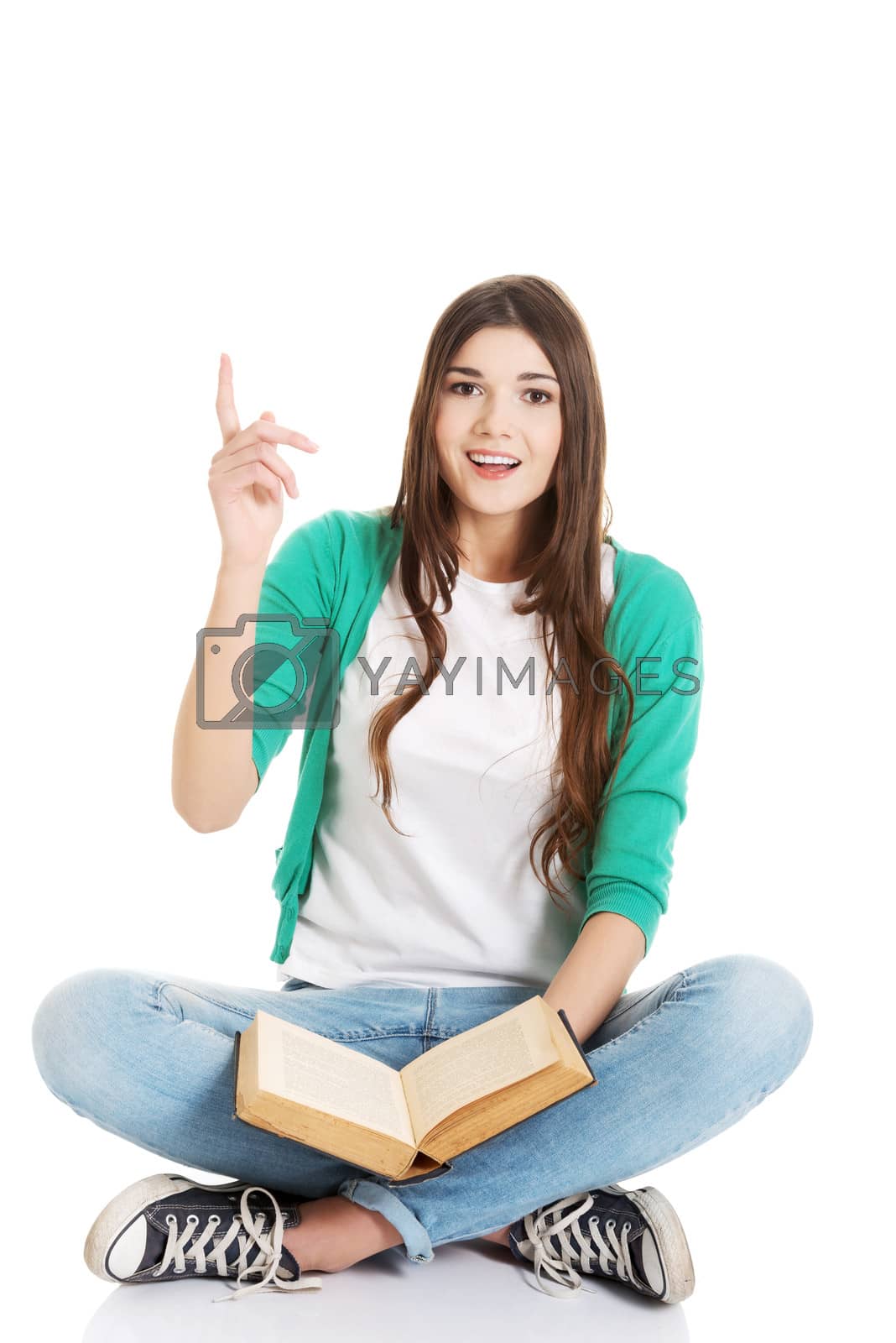 Royalty free image of Young beautiful woman student sitting with book and pointing up. by BDS