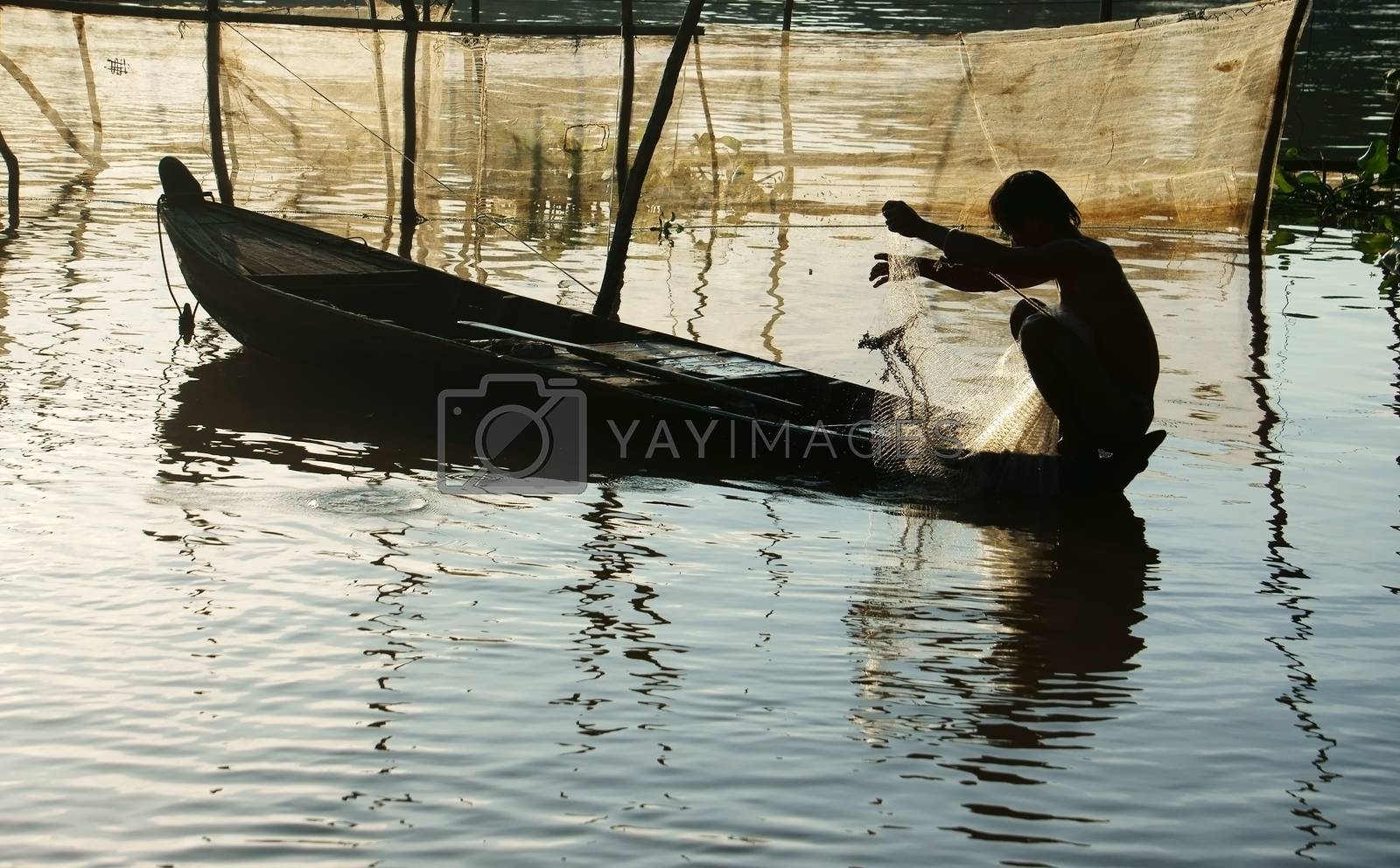 Royalty free image of fisherman sitting on row boat, pick up the net by xuanhuongho
