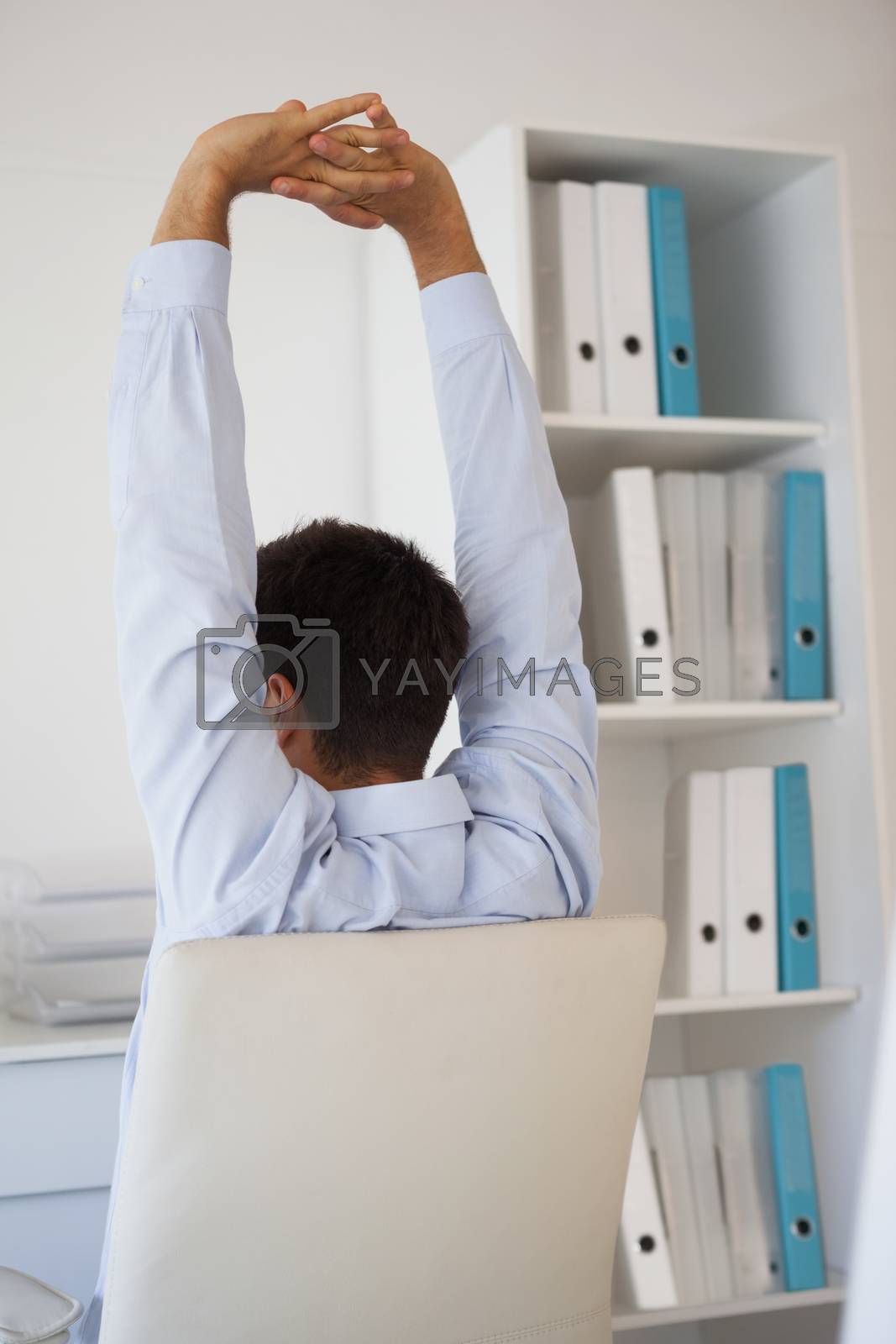 Royalty free image of Casual businessman stretching in swivel chair by Wavebreakmedia