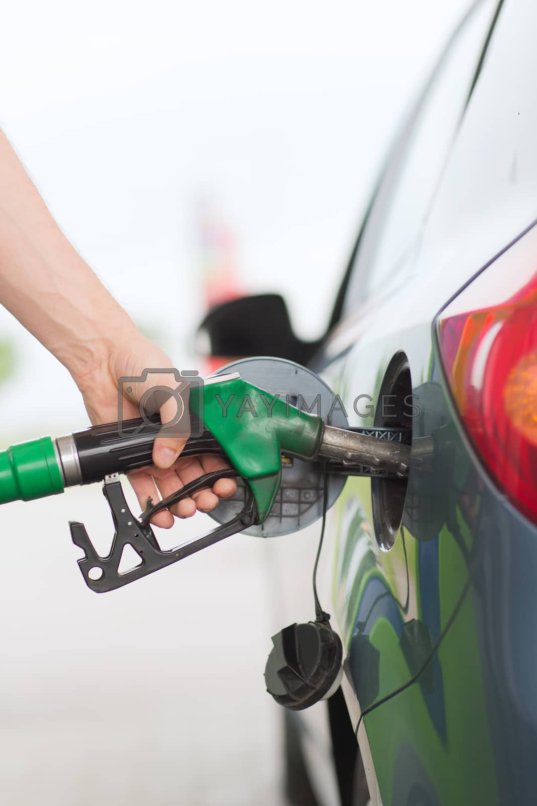 Royalty free image of man pumping gasoline fuel in car at gas station by dolgachov