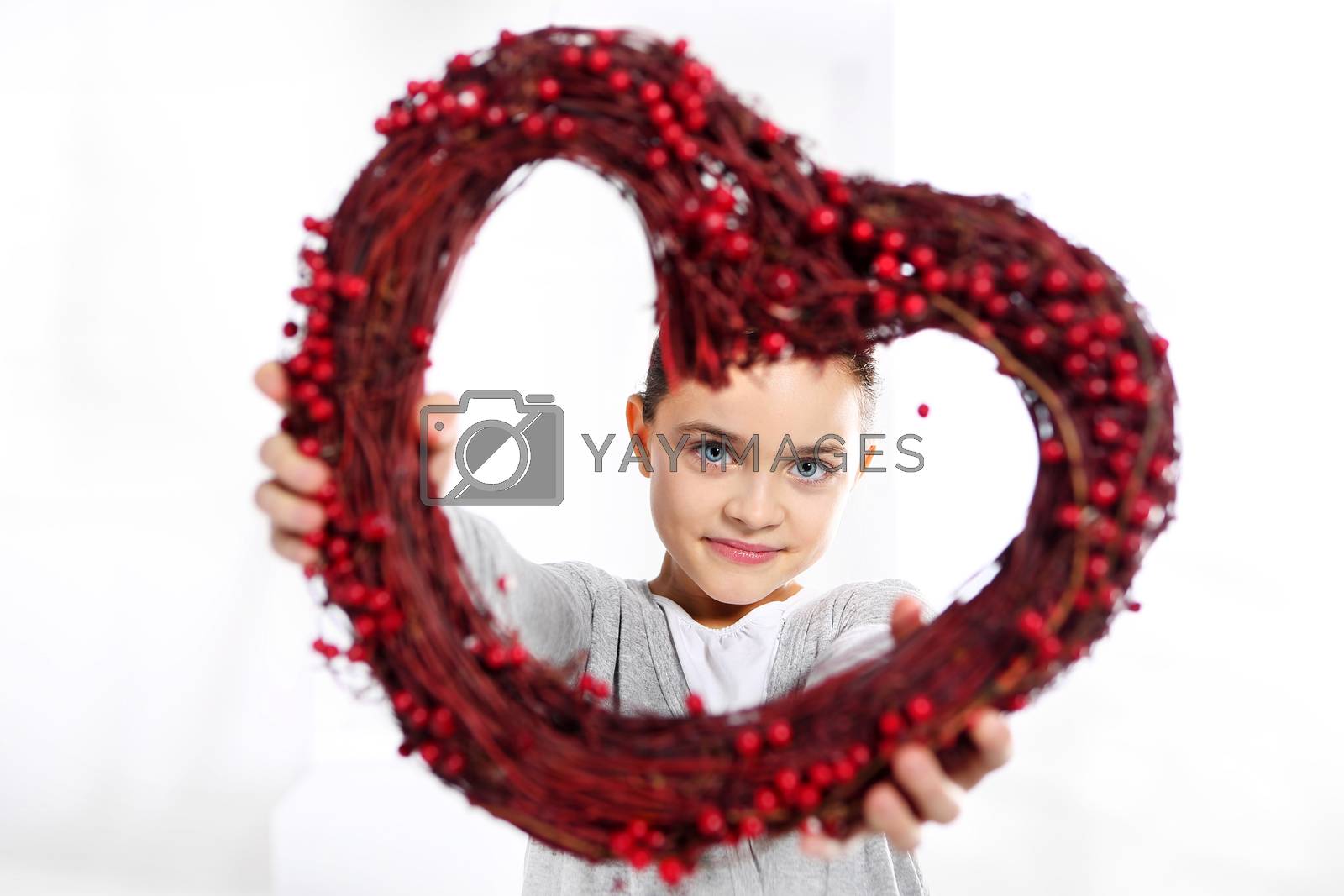 Royalty free image of Caucasian girl looking through a red valentines heart by robert_przybysz