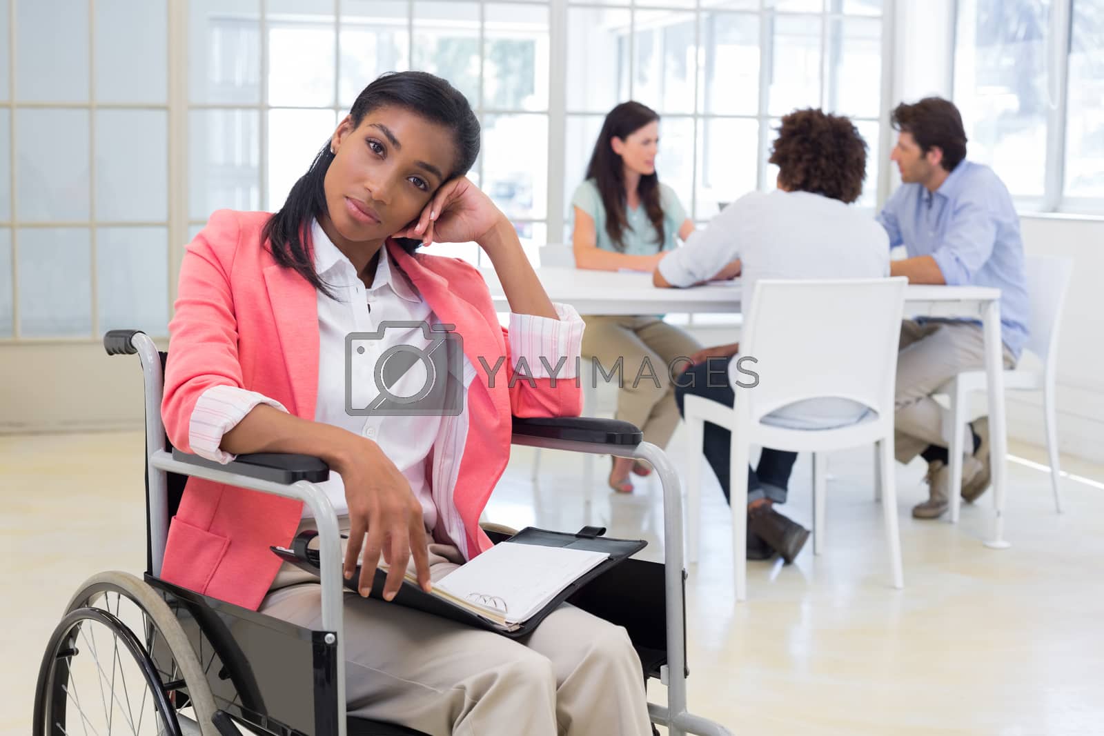 Royalty free image of Woman with disability frowning with coworkers are in background by Wavebreakmedia