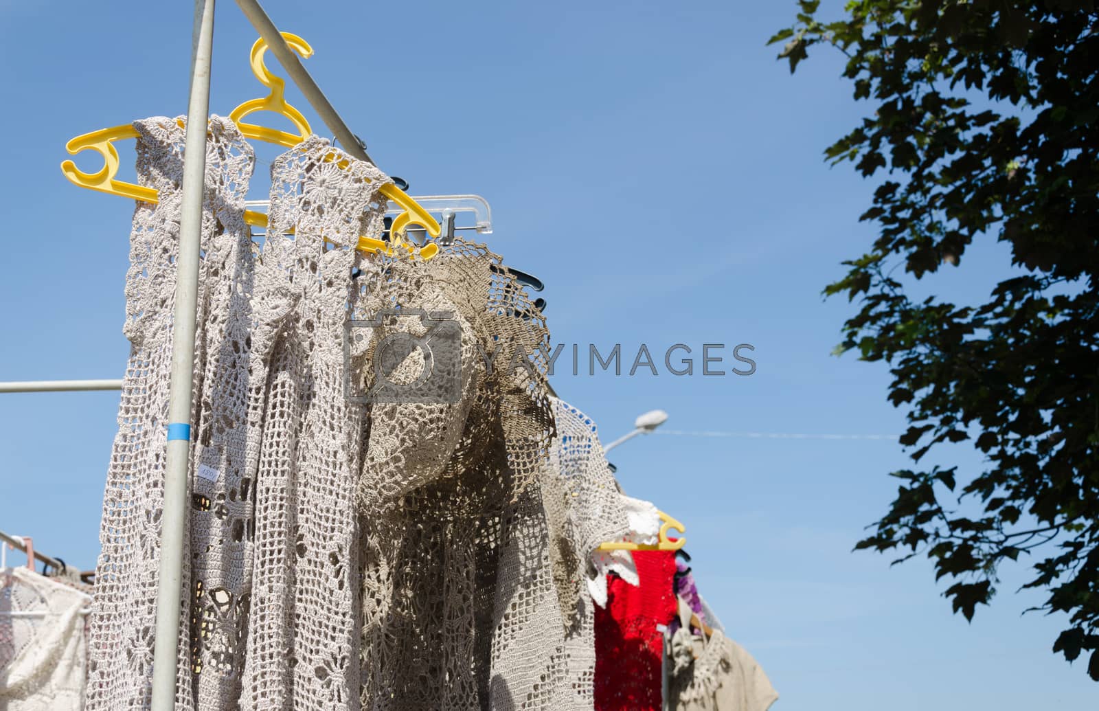 Royalty free image of crocheted linen ladies blouses hang in fair by sauletas