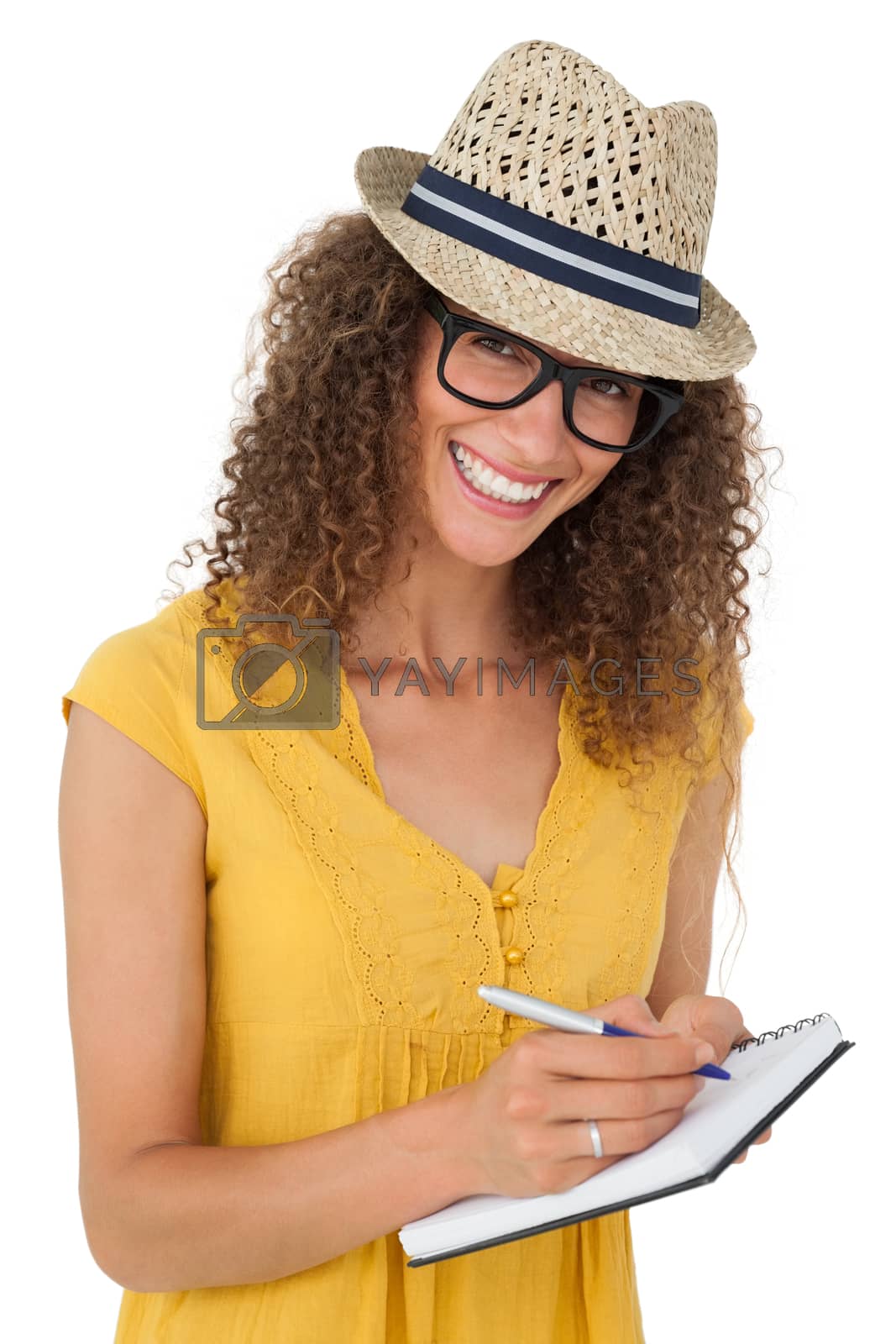 Royalty free image of Cheerful young woman writing in notepad by Wavebreakmedia