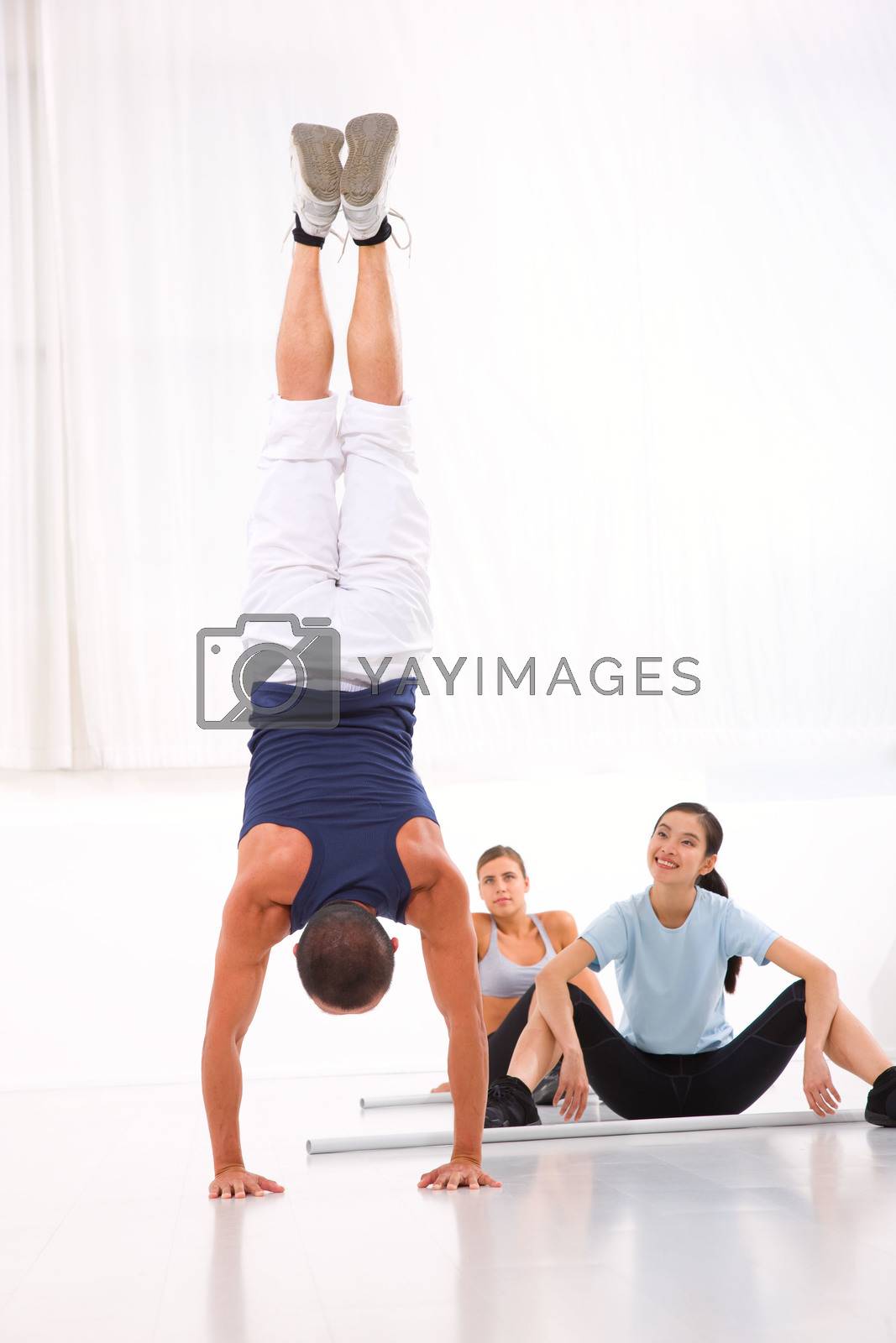 Royalty free image of Asian woman looking man doing handstand exercise by ambro