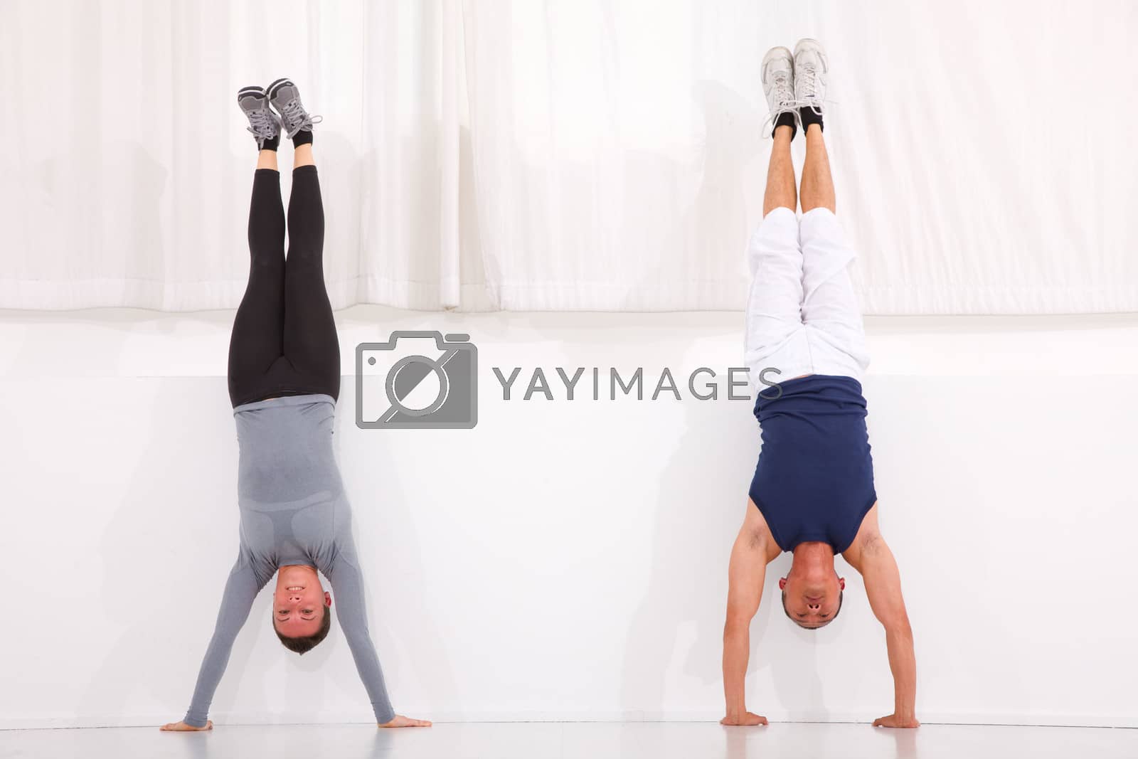 Royalty free image of Man and woman doing handstand exercise in gym by ambro