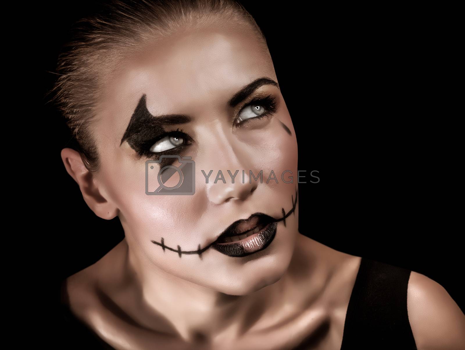 Portrait of aggressive young woman with creepy makeup and black tear isolated on black background, Halloween celebration concept