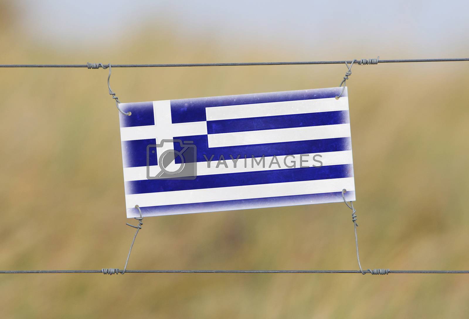Royalty free image of Border fence - Old plastic sign with a flag by michaklootwijk