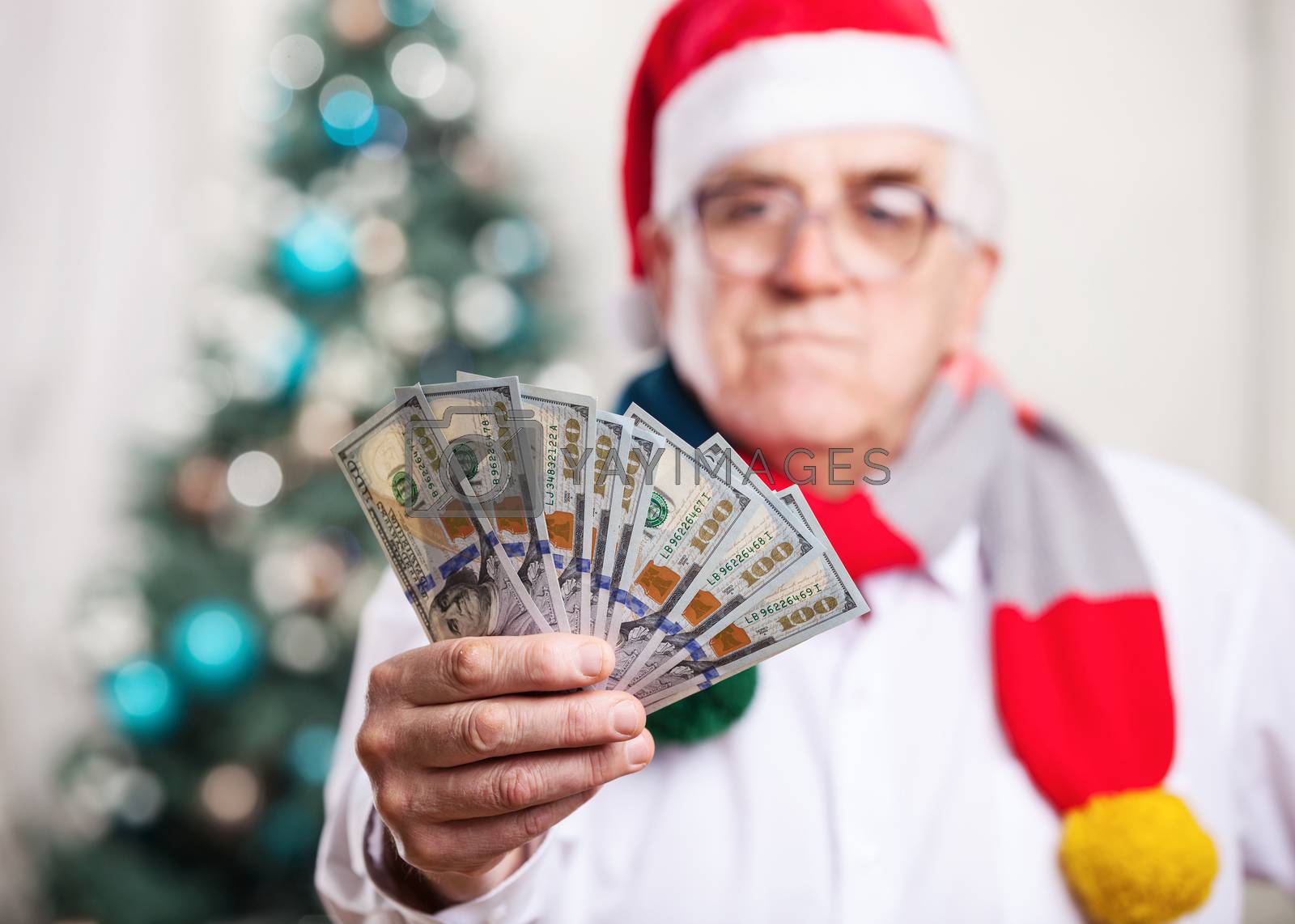 Royalty free image of Man in Santa's hat holding money, hand in focus by photobac